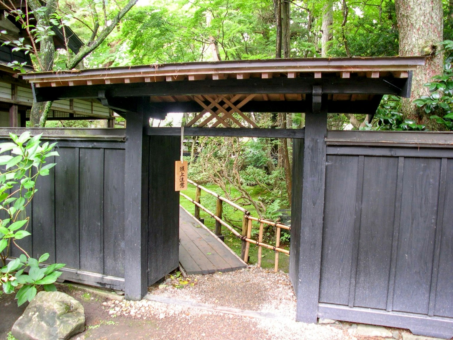 Entrada de jardín japonés con puerta de madera negra y camino