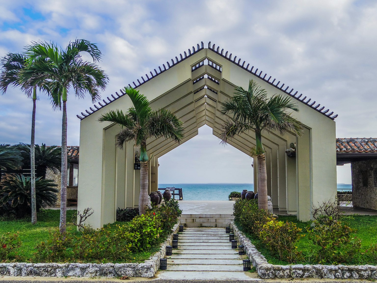 Arch-shaped building with palm trees and ocean view