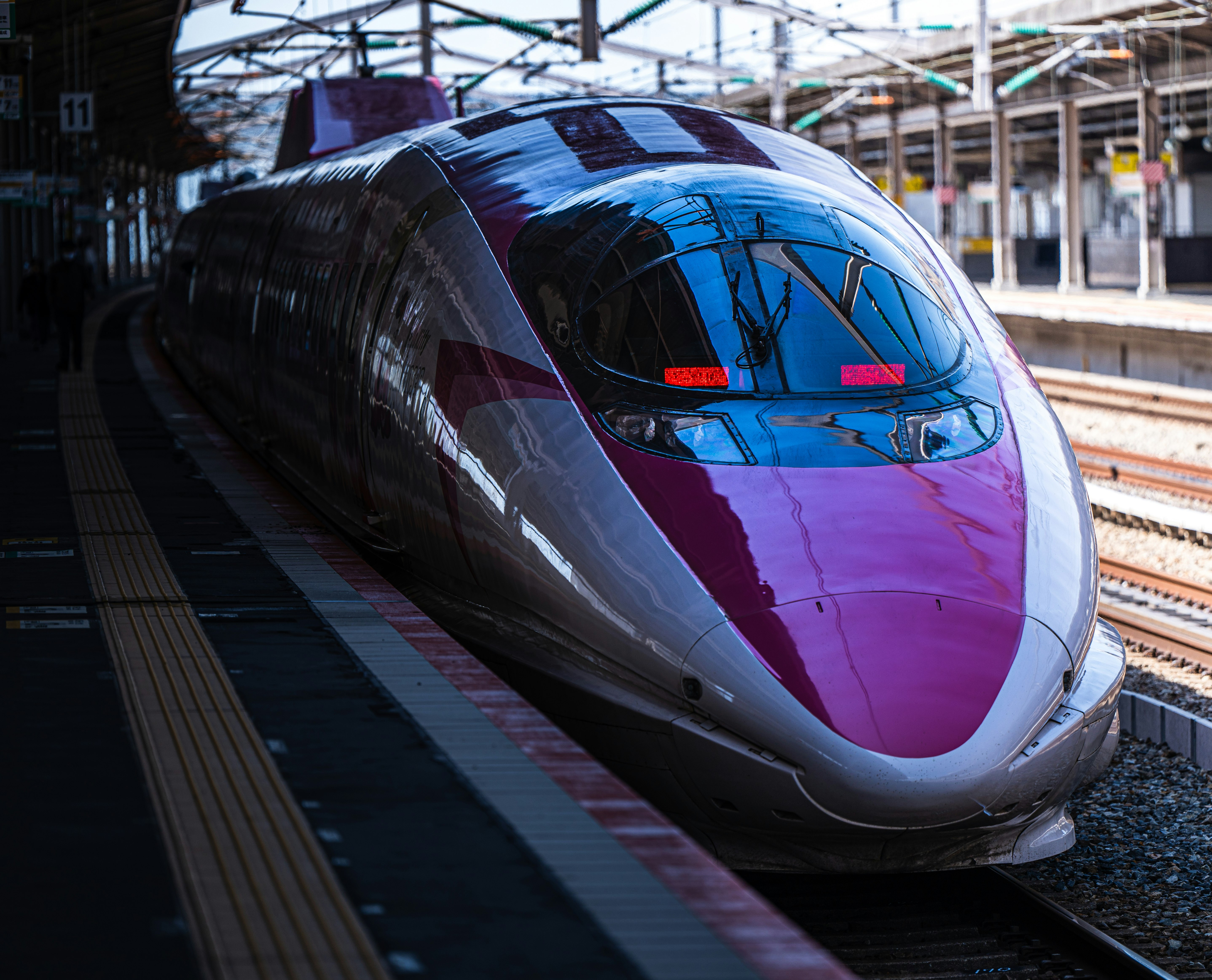 在車站的新幹線列車，粉紅色和銀色設計
