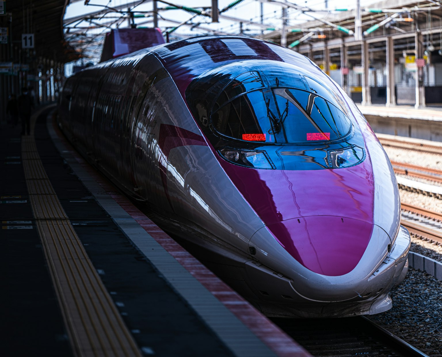 Treno Shinkansen in stazione con un design rosa e argento