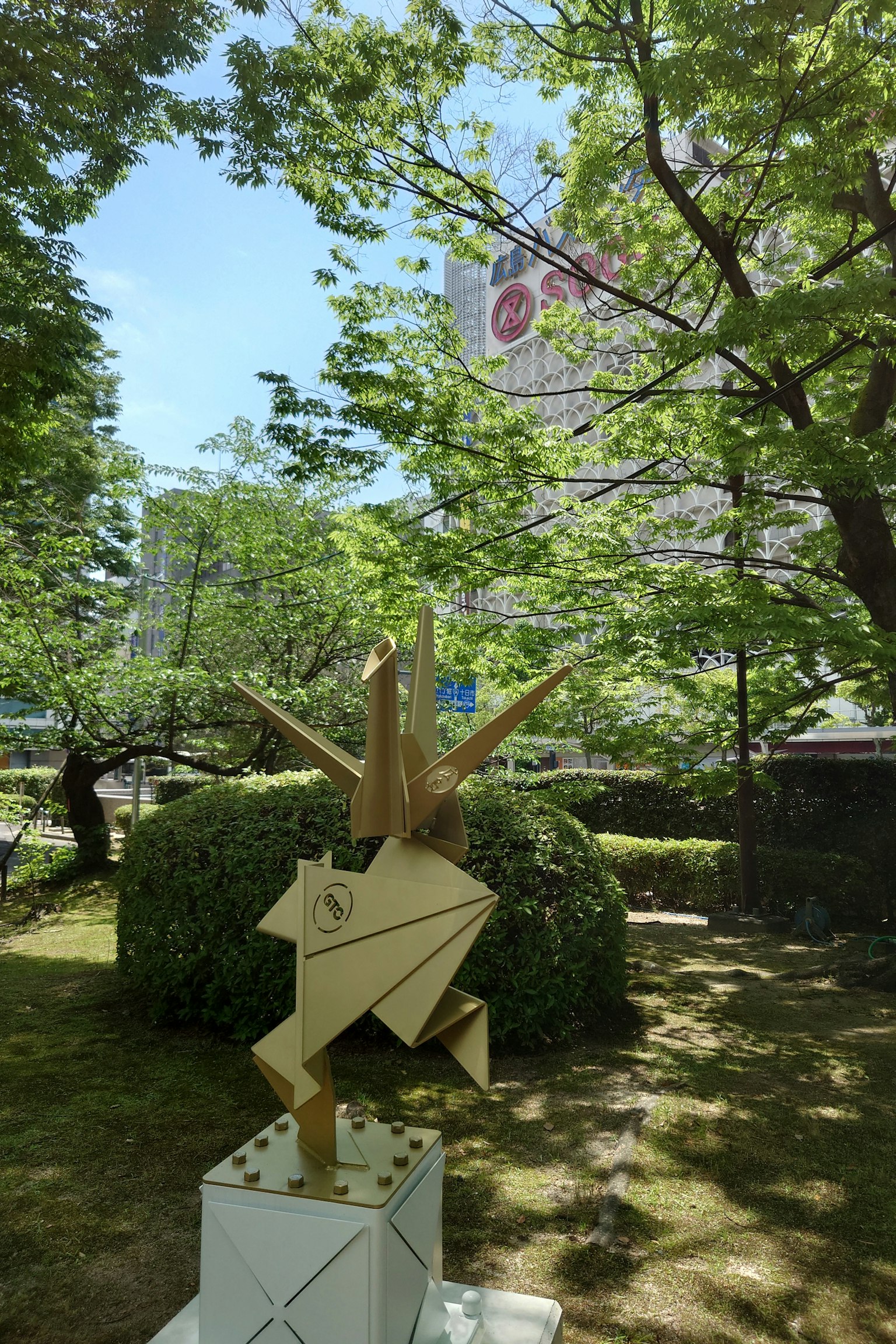 Una escultura dorada con forma de origami en un entorno de parque