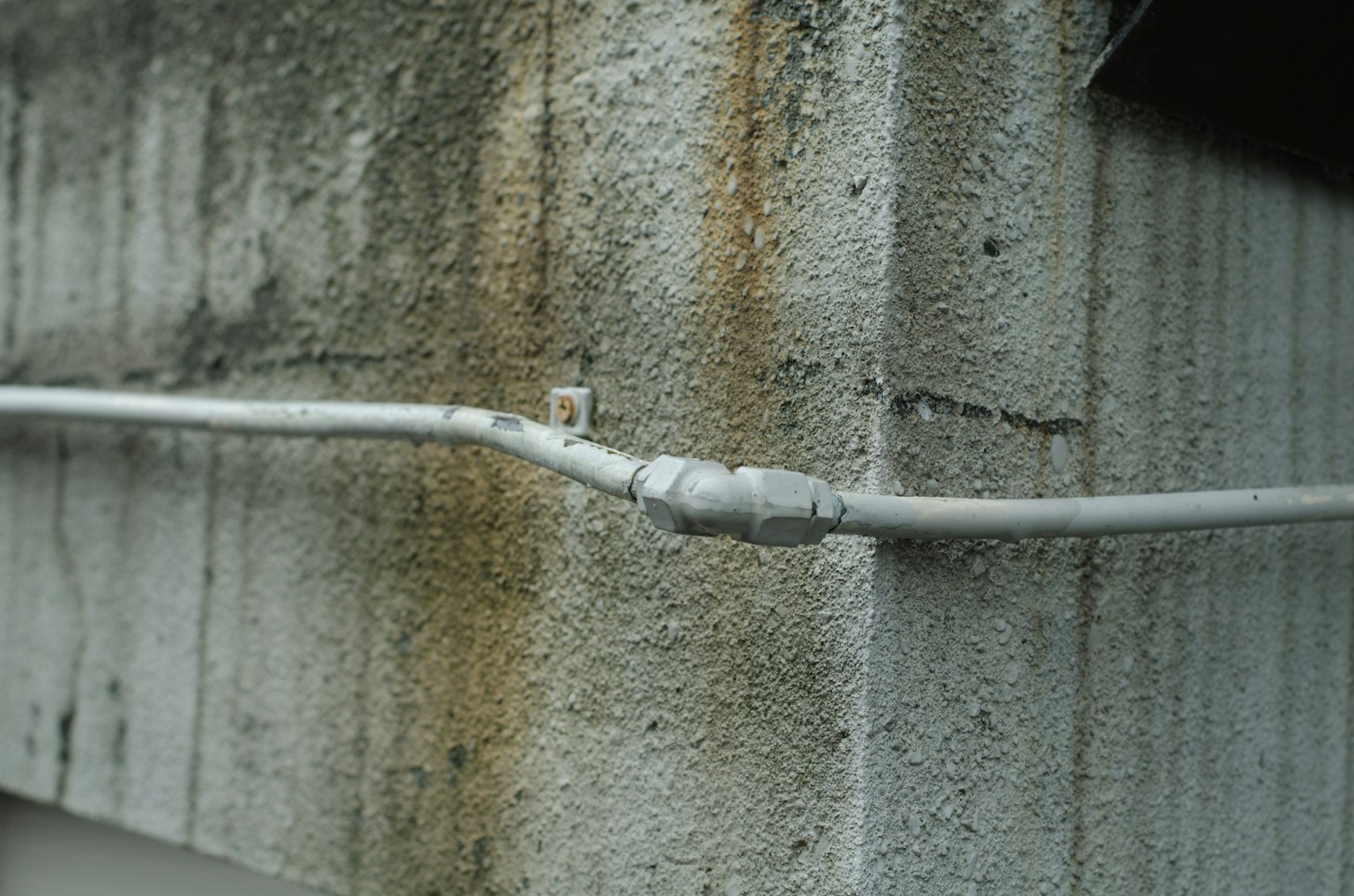 Gros plan sur un raccord de tuyauterie métallique le long d'un mur en béton