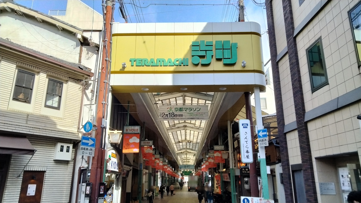 Entrada a una calle comercial con un letrero y una arcade