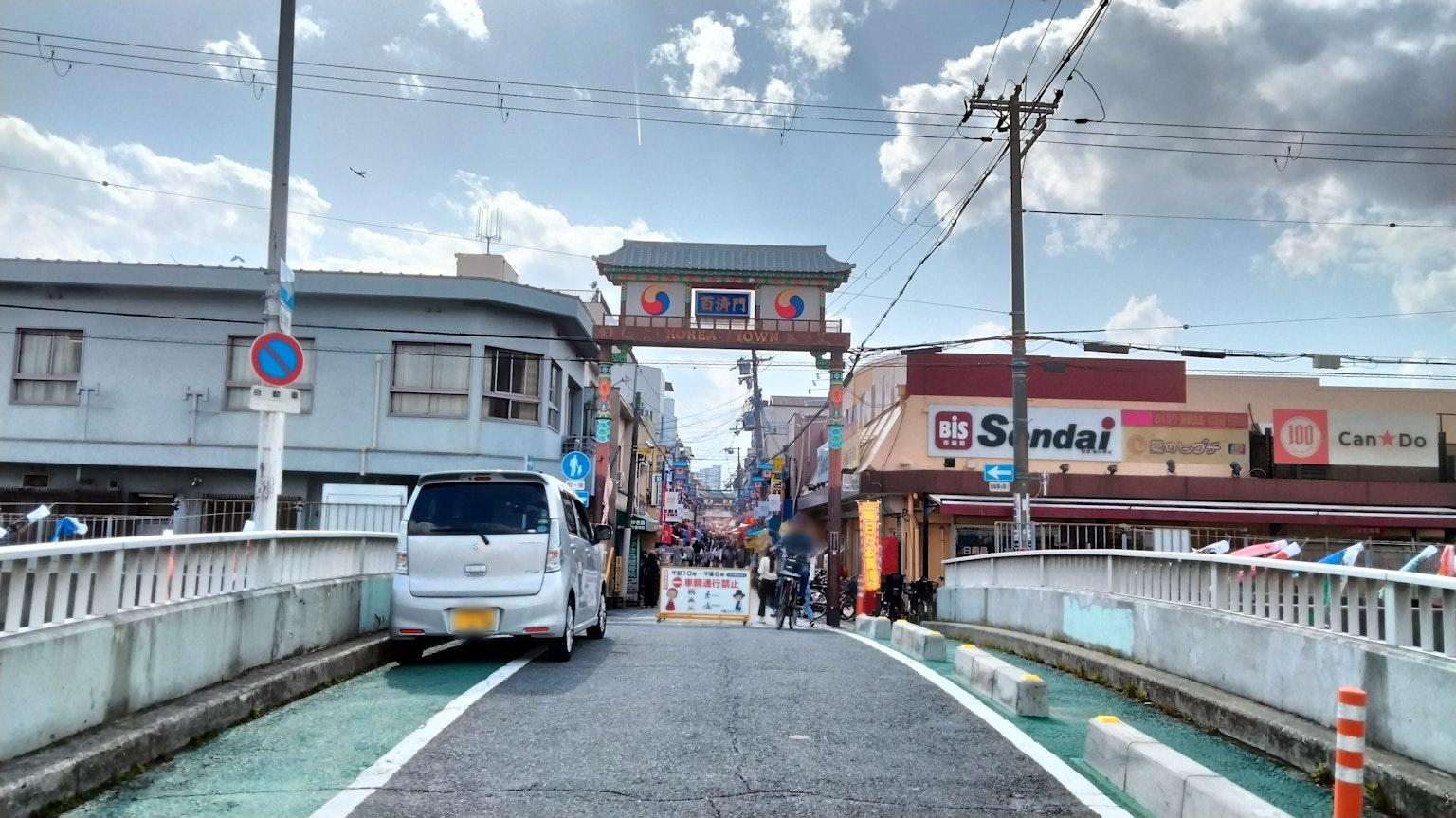 Vue d'une rue avec un pont menant à une entrée en arc d'une zone commerçante