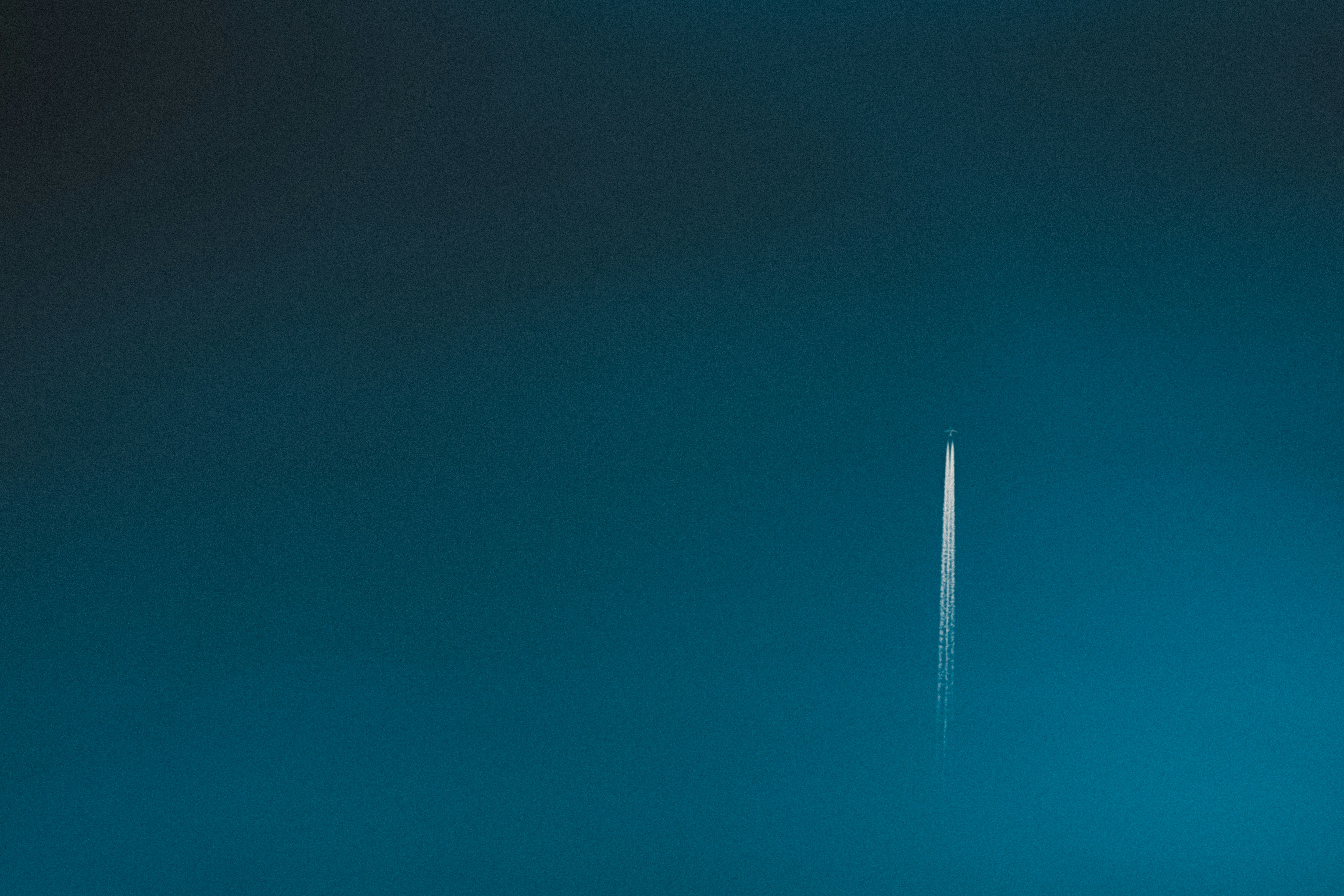 青い空に細い飛行機雲が伸びる空の風景