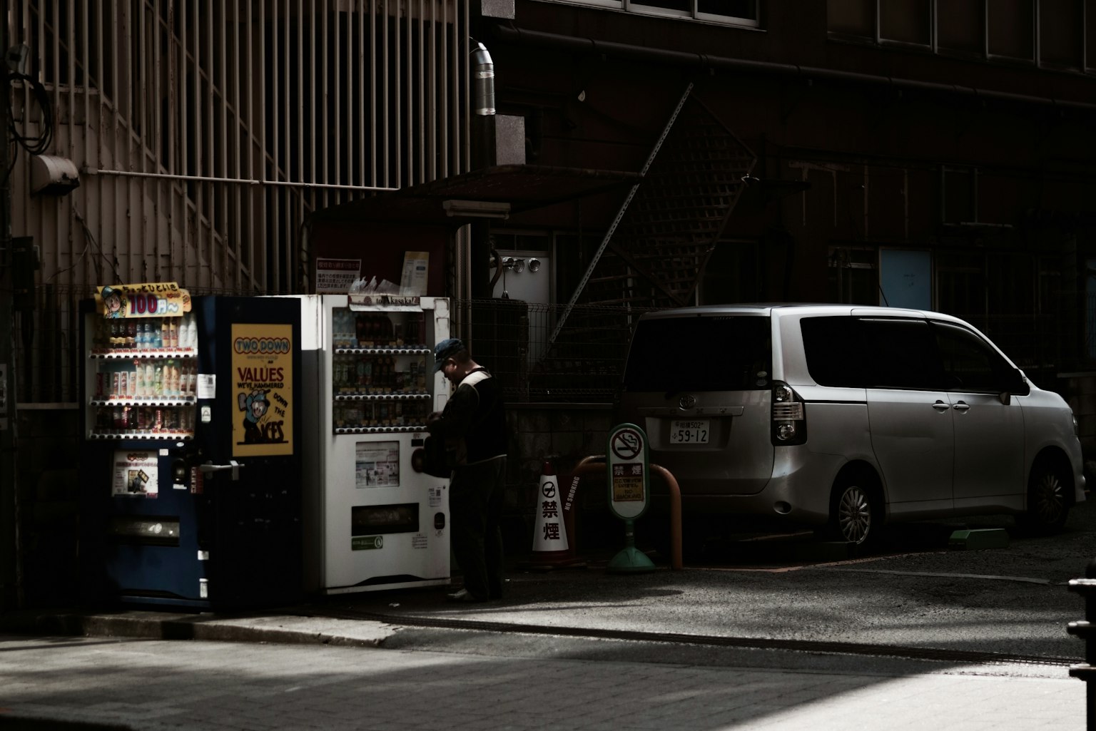 昏暗的街道場景,展示了一個自動販賣機和一輛停著的車