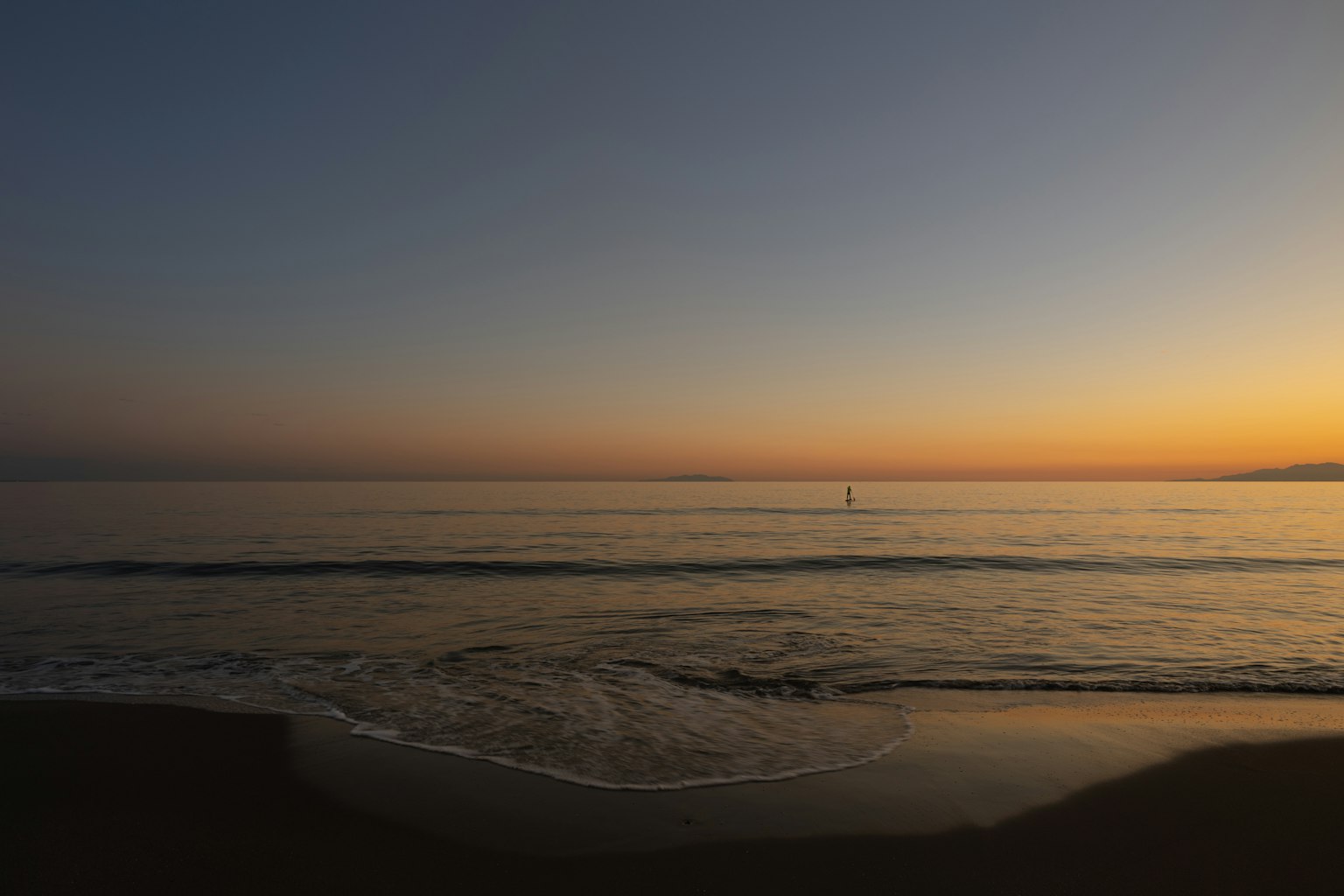 Coucher de soleil sur l'océan avec des vagues douces et un ciel orange