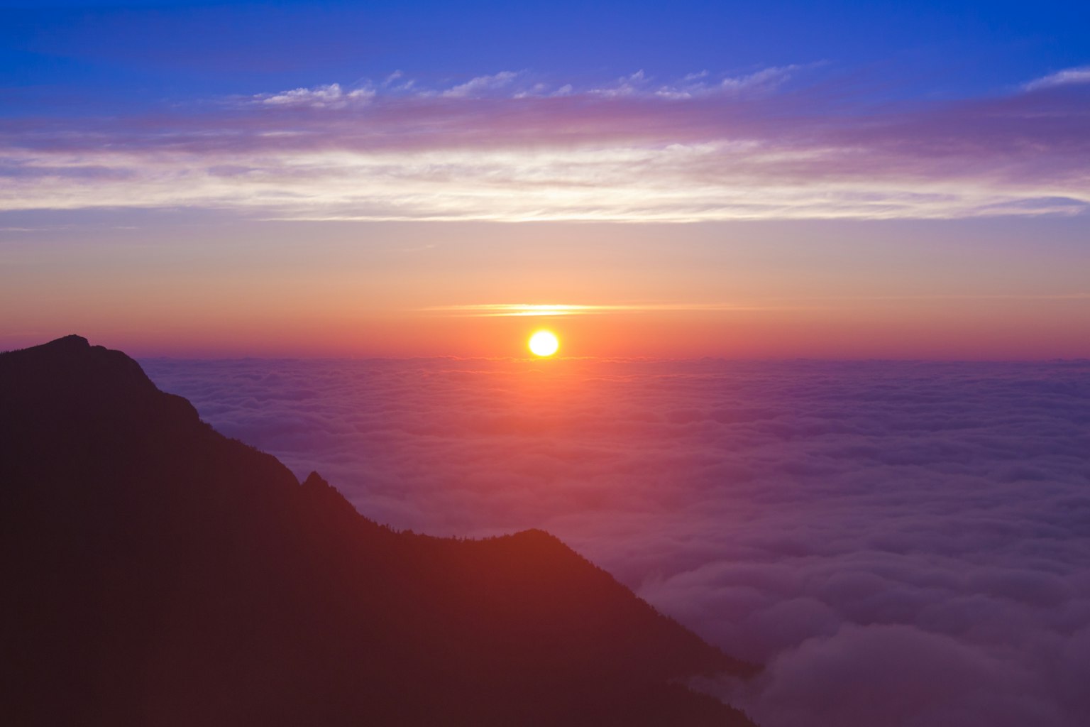 Splendido sorgere del sole visto da una cima sopra un mare di nuvole