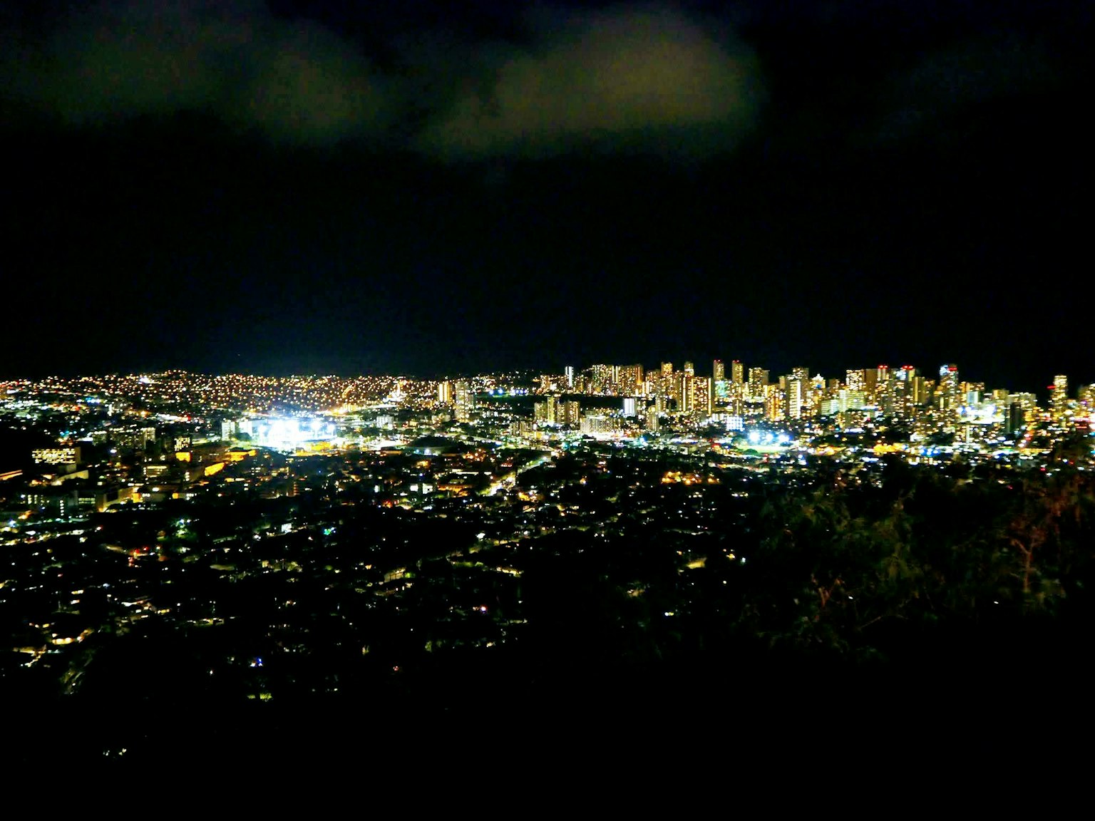 Vue panoramique d'une ville la nuit avec des lumières vives et un ciel sombre