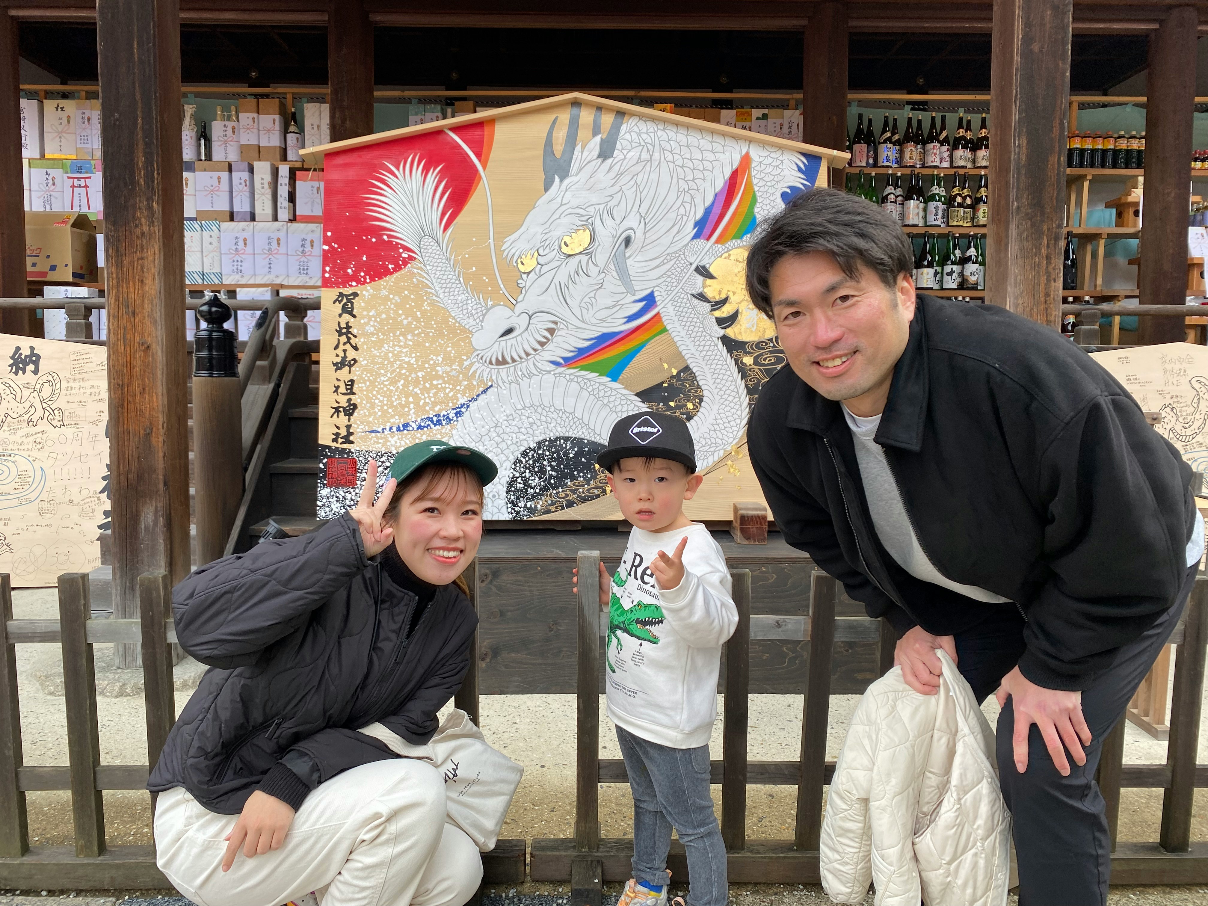 Family posing at a liquor shop entrance with a large eagle mural