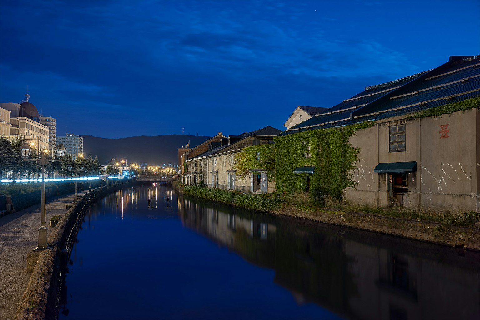 Vista nocturna de un canal con edificios antiguos y reflejos