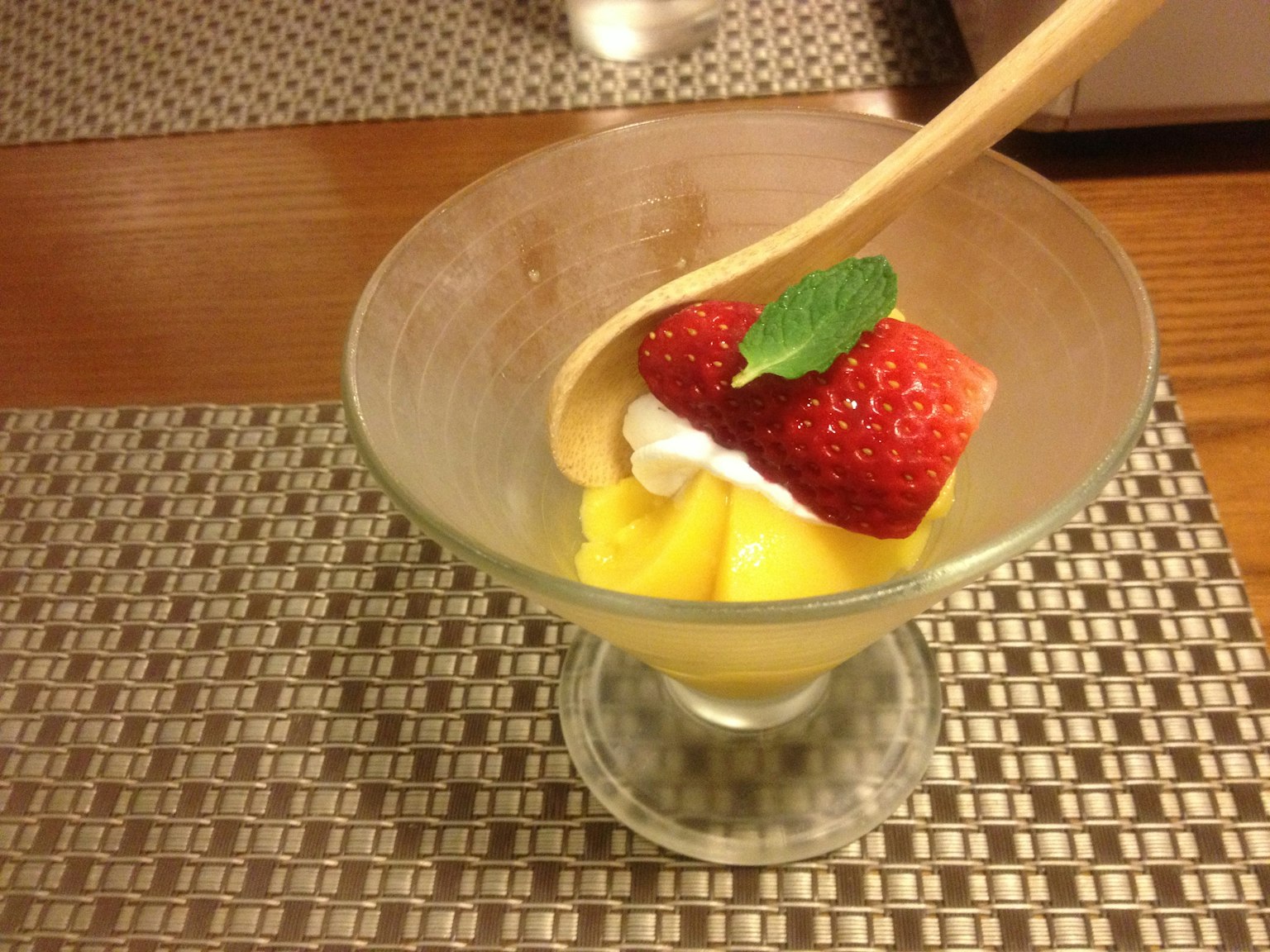 Eine schöne Dessertschale gefüllt mit Mango-Eis, garniert mit frischen Erdbeeren und einem Minzblatt