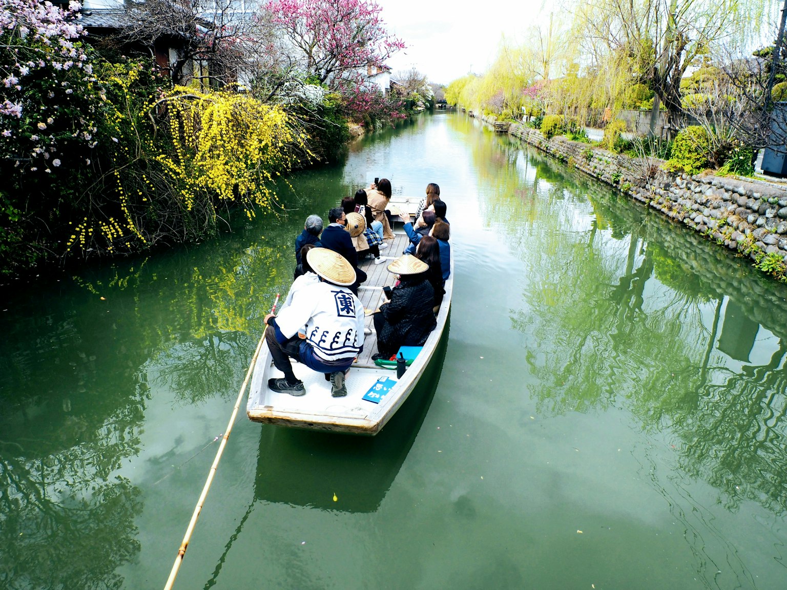 Gruppo di persone su una barca in un canale tranquillo circondato da vegetazione lussureggiante