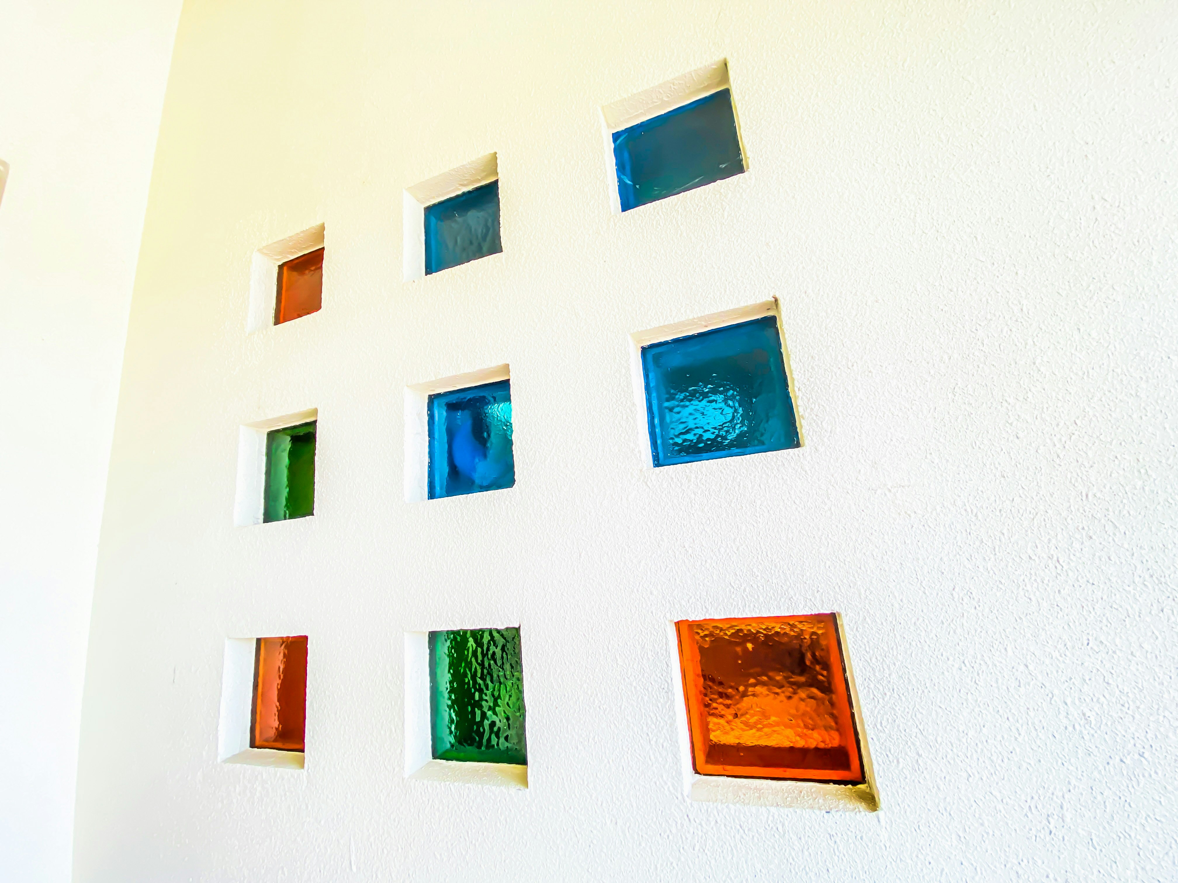 parete bianca con una griglia di finestre quadrate in vetro colorato
