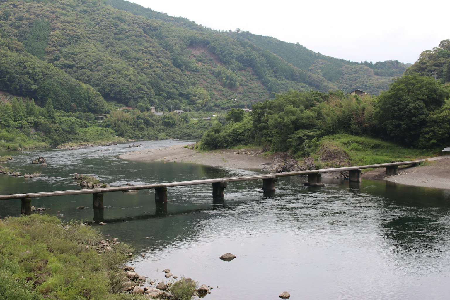 Image d'un pont traversant une rivière entourée de montagnes