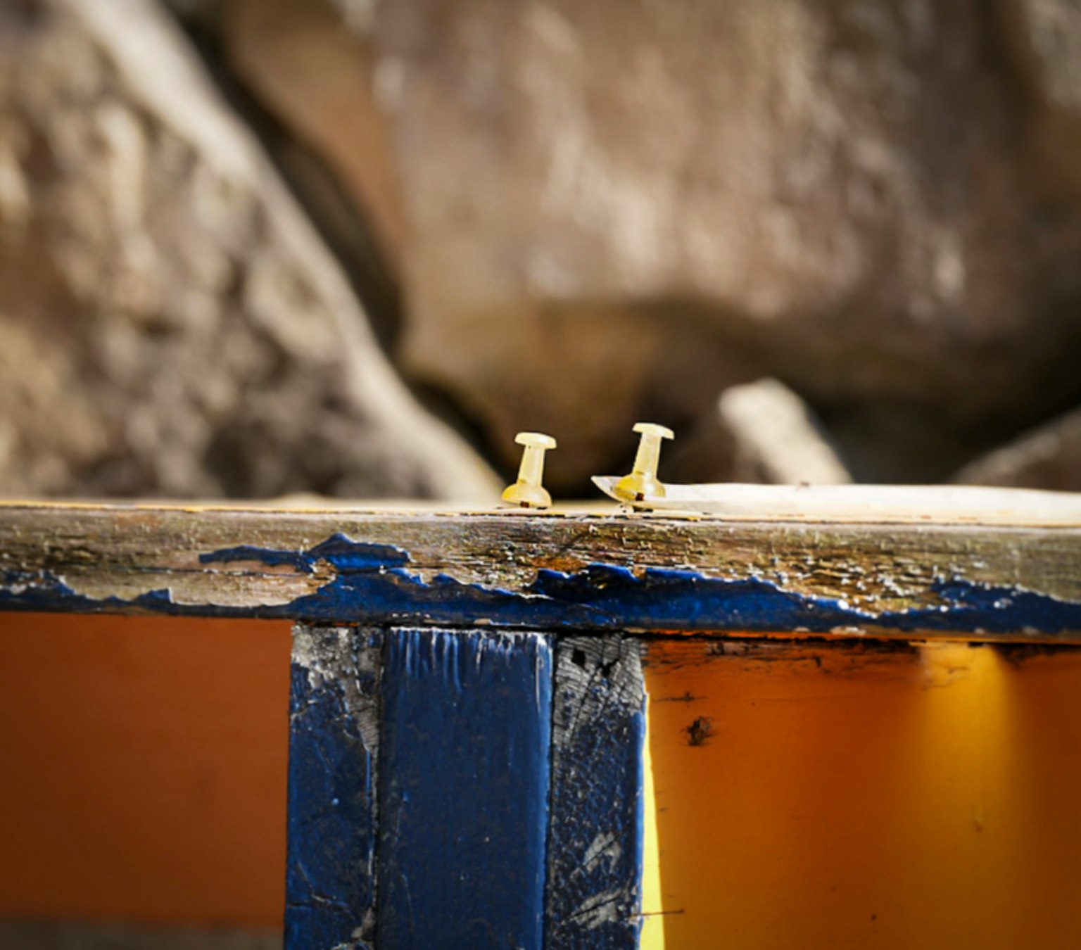 Zwei kleine Metallstifte auf einer gelben und blauen Holzoberfläche
