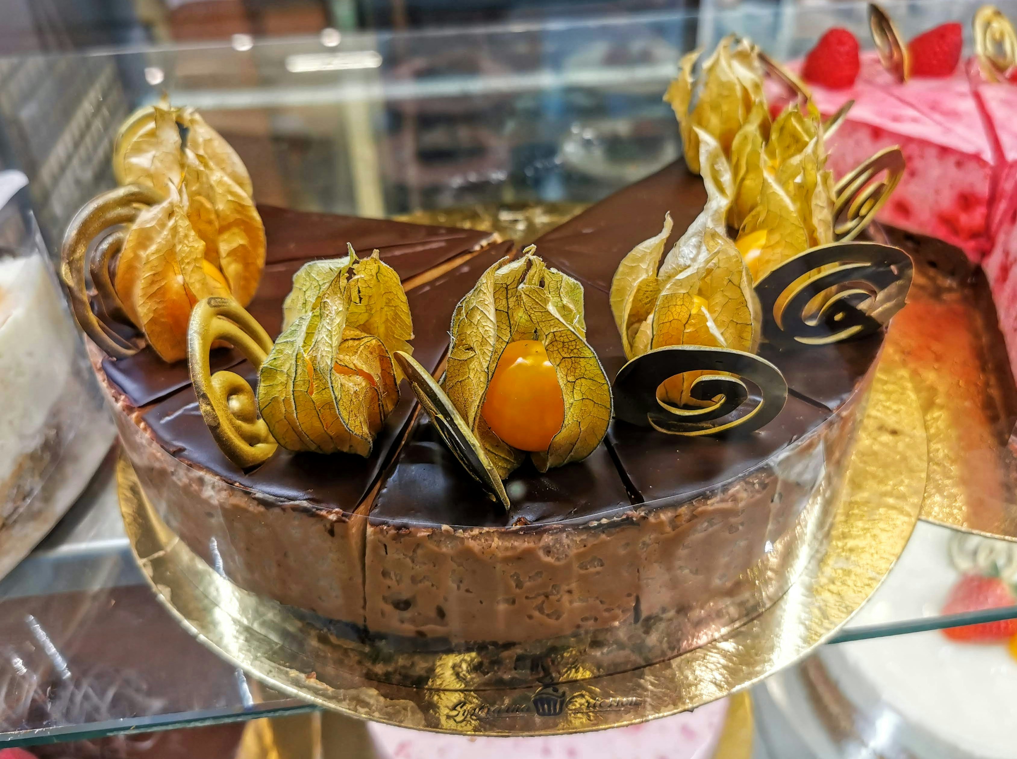 ガラスケース内の金色の焼き菓子とチョコレートの盛り合わせ