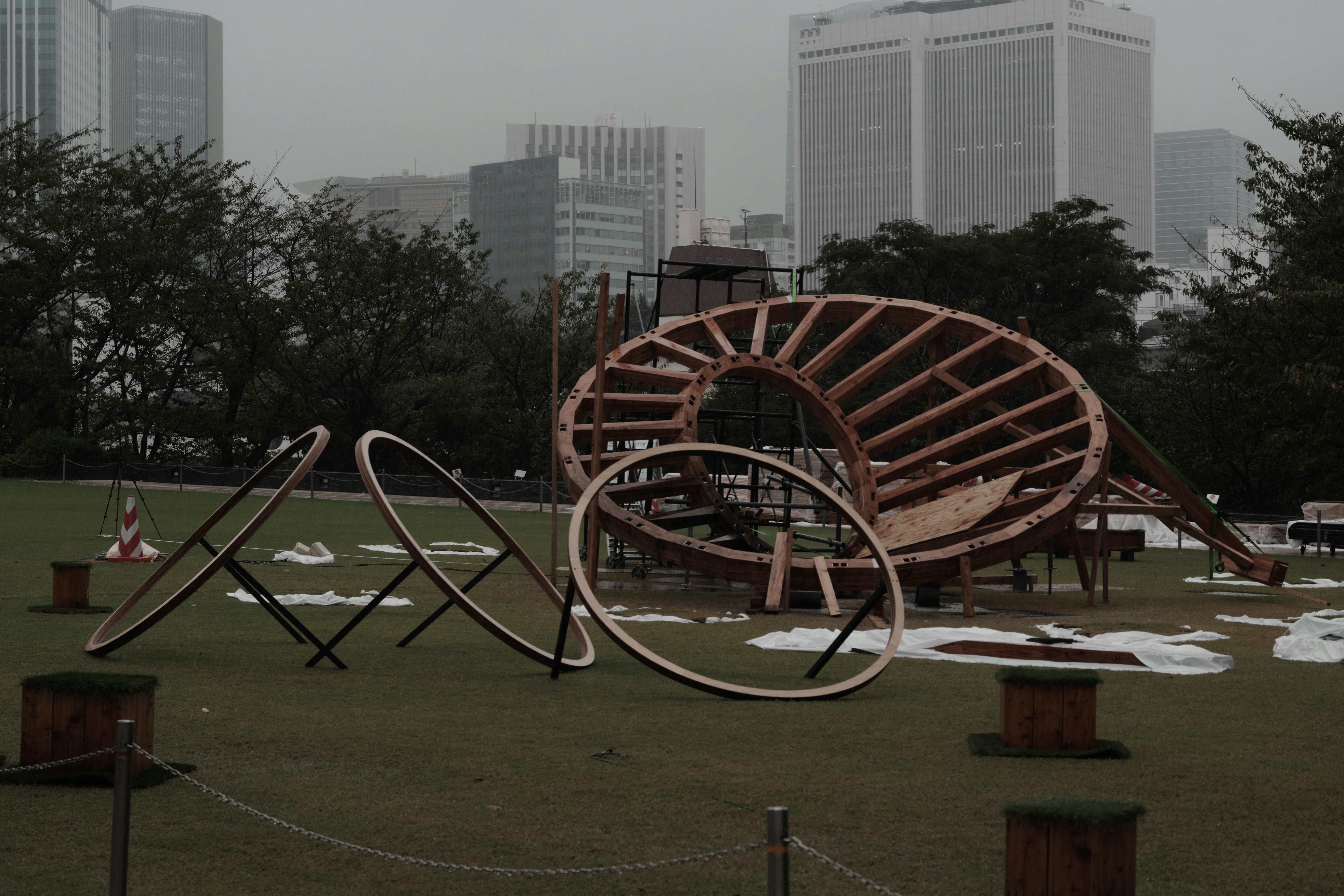 雨の中の公園でイベント準備が進む屋外展示のオブジェ「画像」