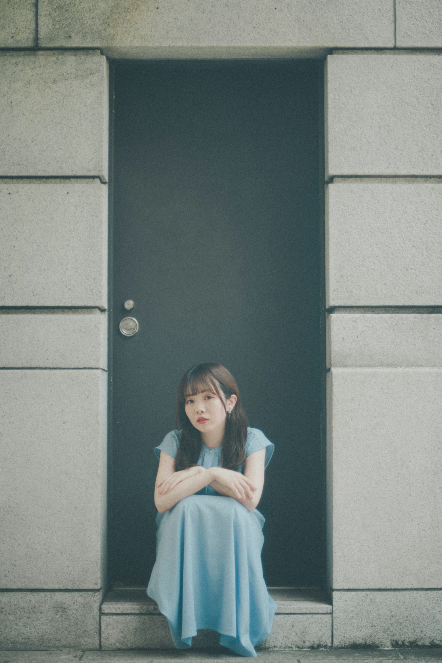 穿着蓝色连衣裙的女人坐在门前