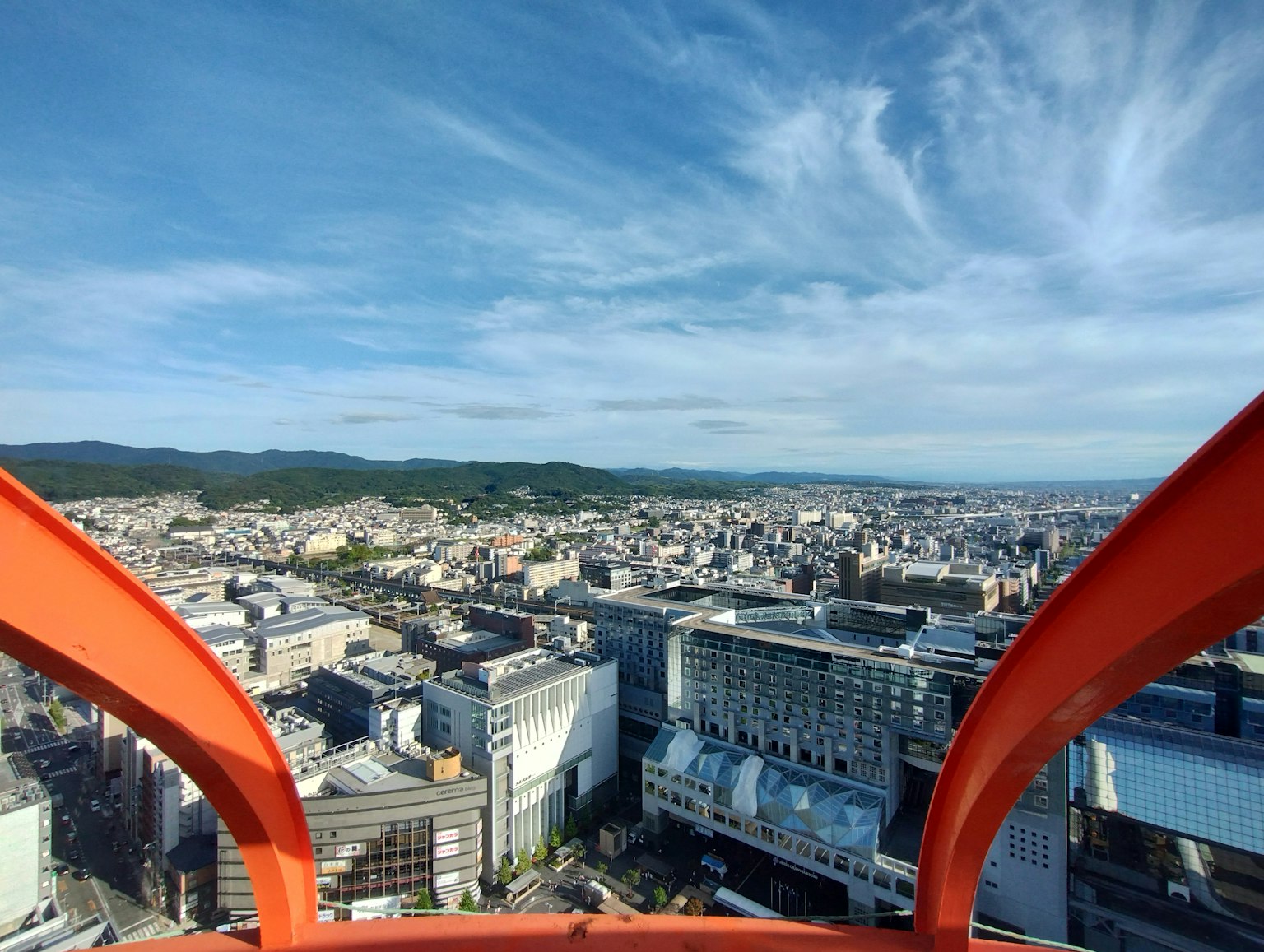 Pemandangan langit Osaka dan gedung-gedung melalui struktur oranye