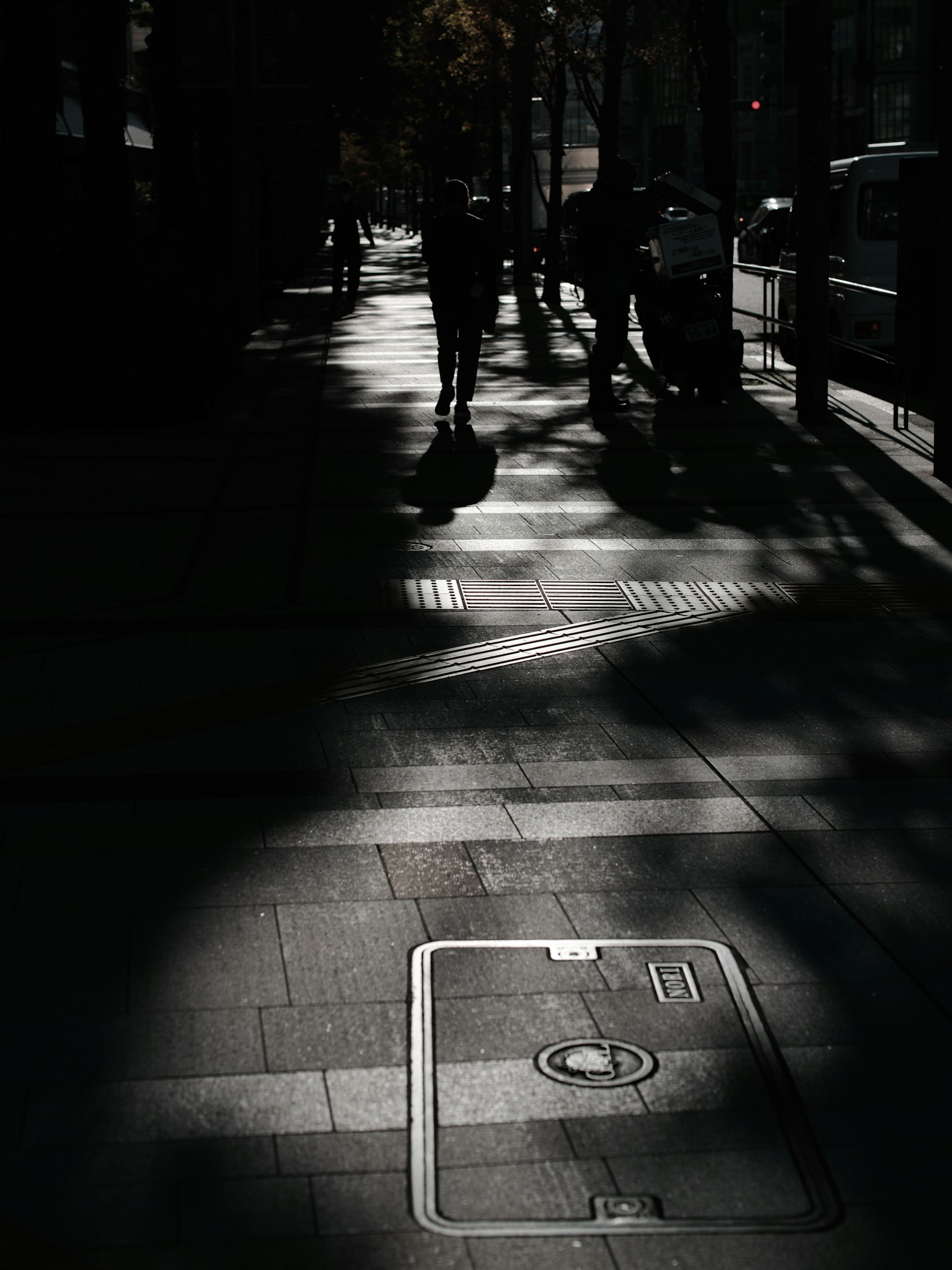 Schwach beleuchtete Straße mit Schatten und Silhouetten von Menschen