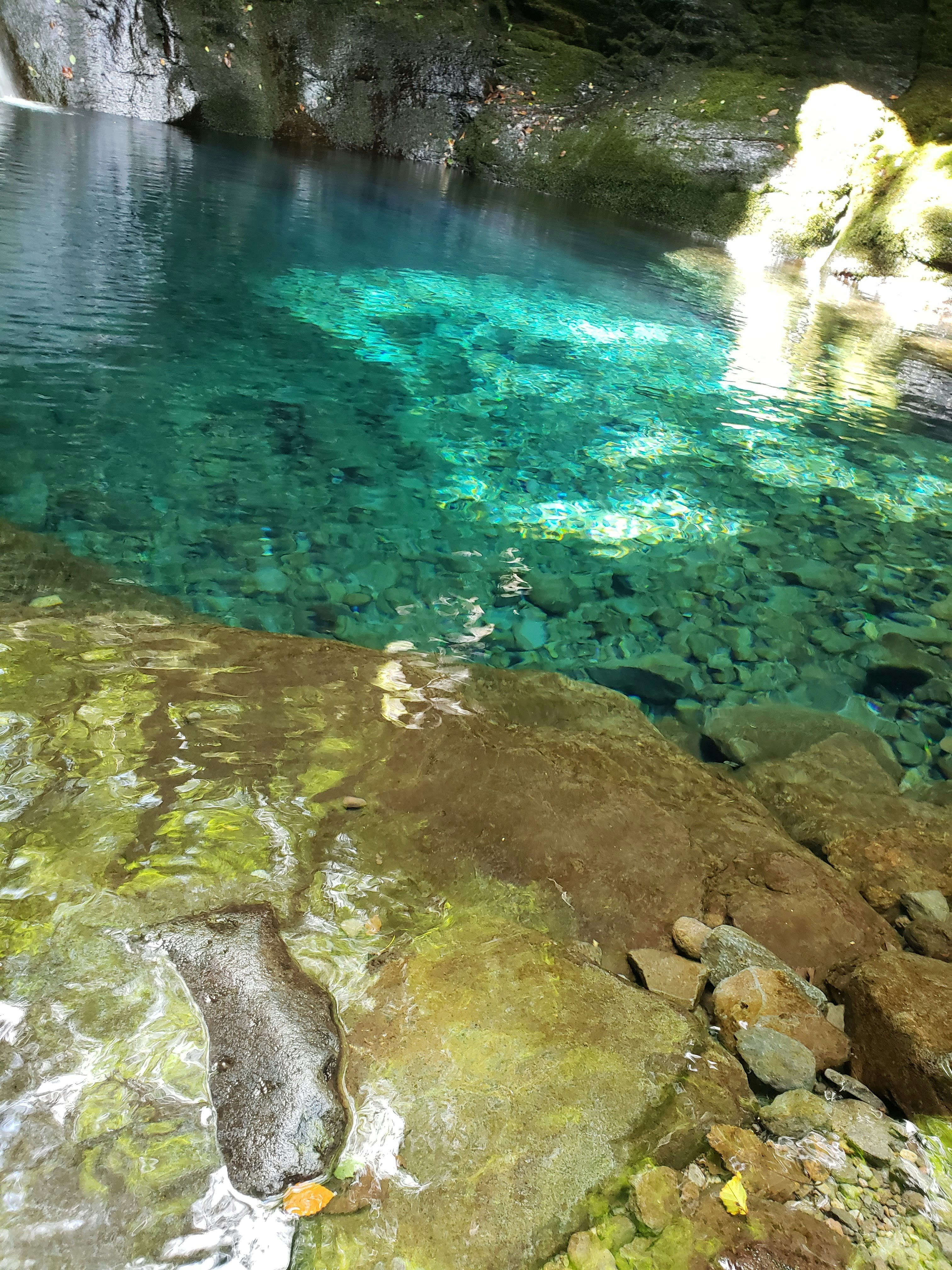 エメラルド色の澄んだ滝壺と岩の渓流