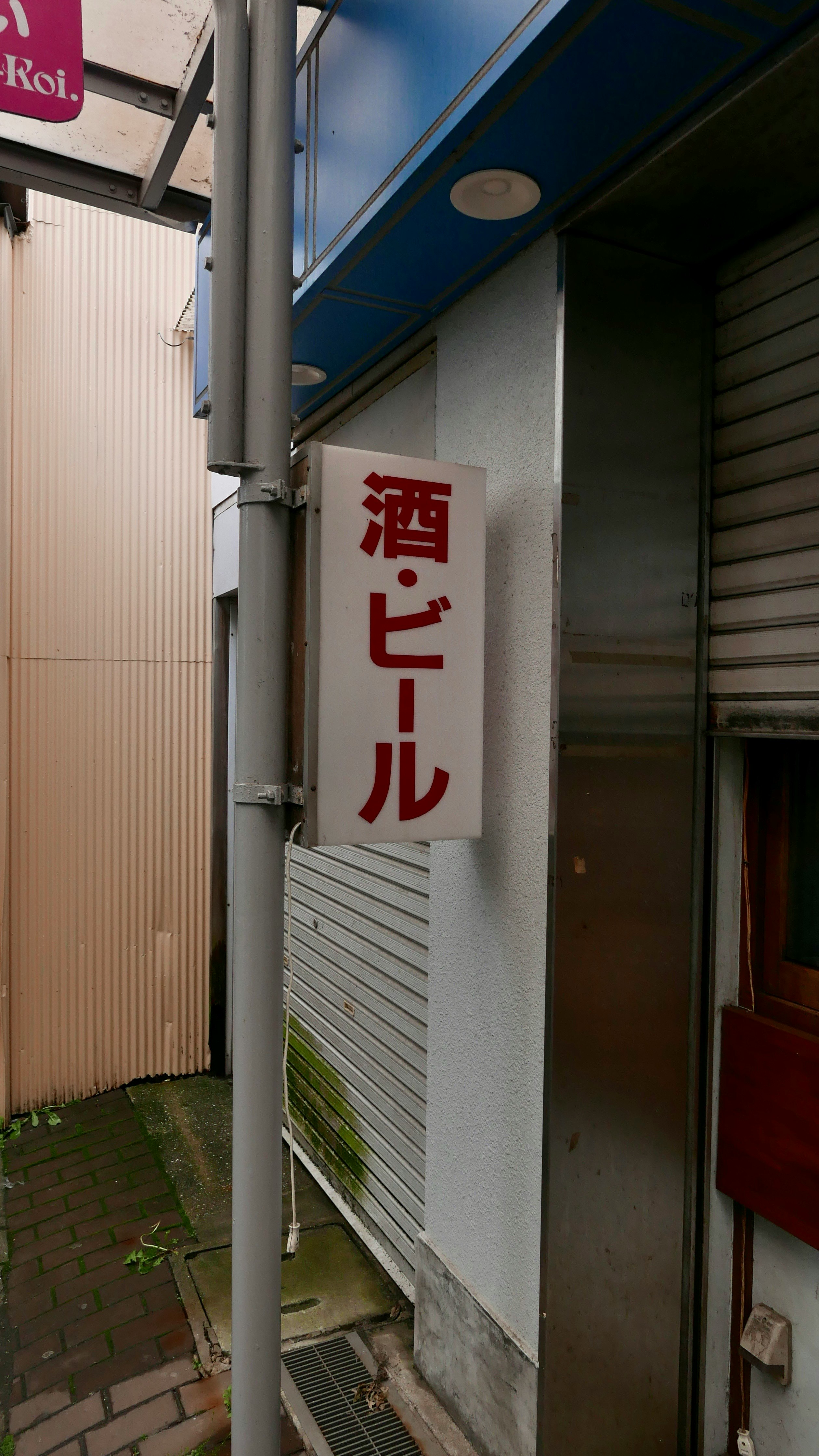 酒・ビールの看板が掛かった路地の壁