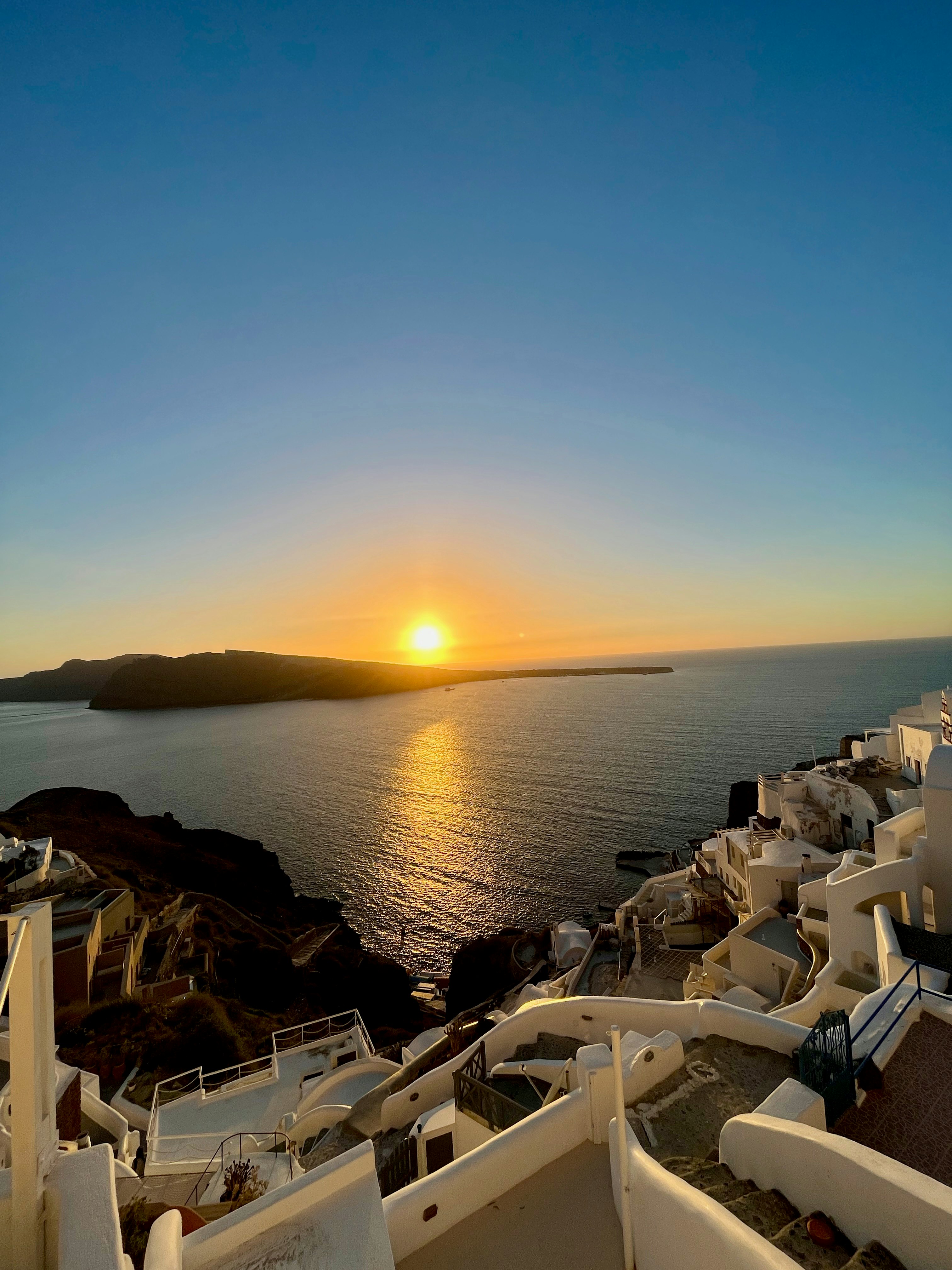 サントリーニ島イアの白い家並みと夕日が海に沈む景色
