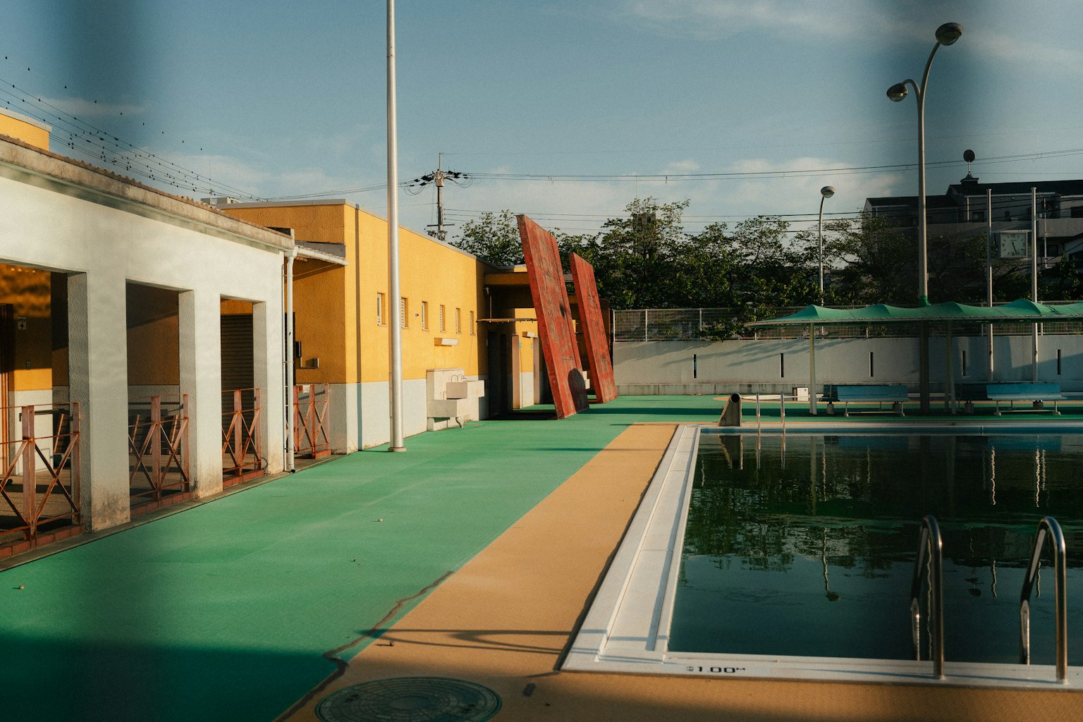 Vue d'une piscine avec des bâtiments environnants couleurs vives et sol vert