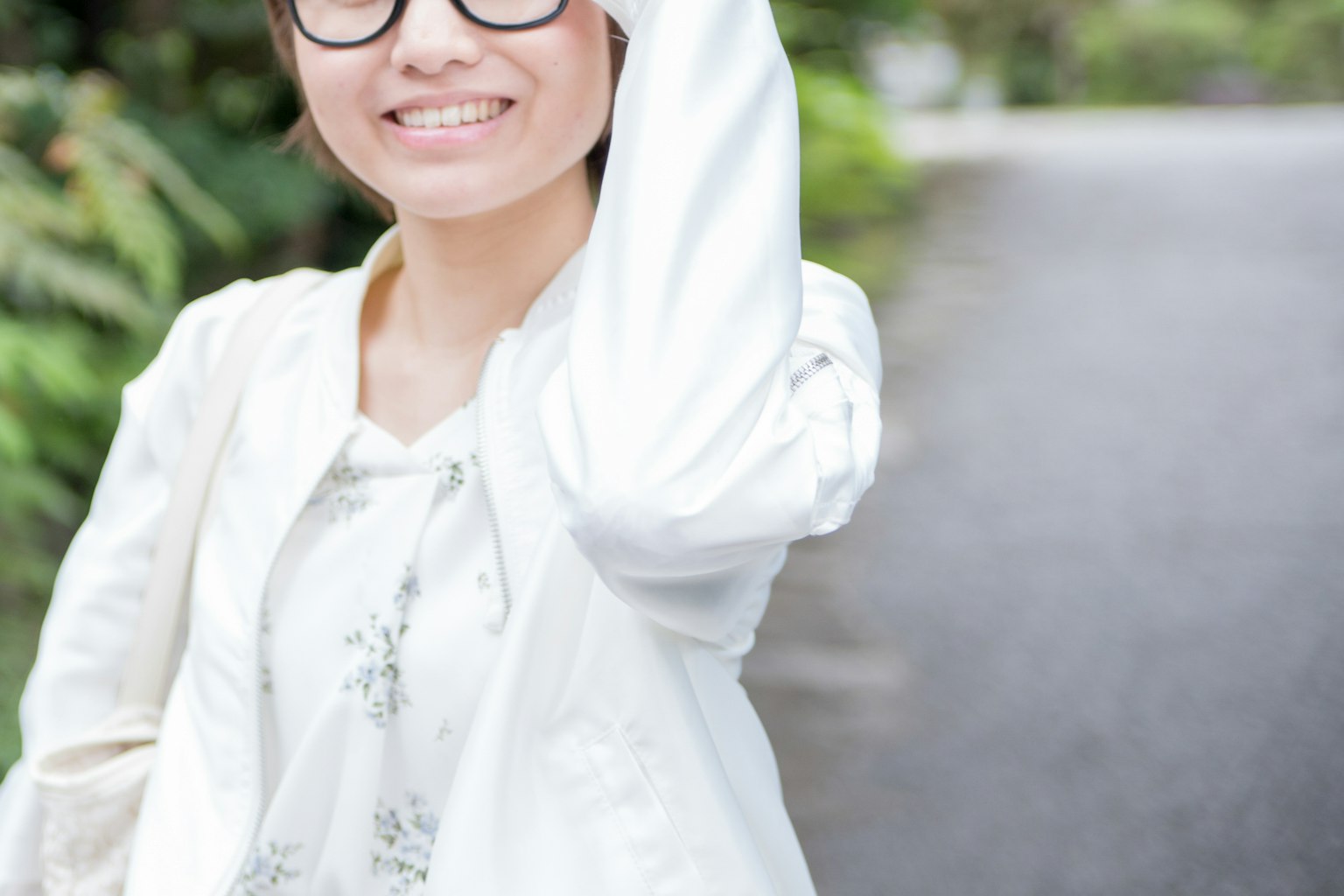 หญิงสาวยิ้มในชุดสีขาวเดินอยู่บนถนน