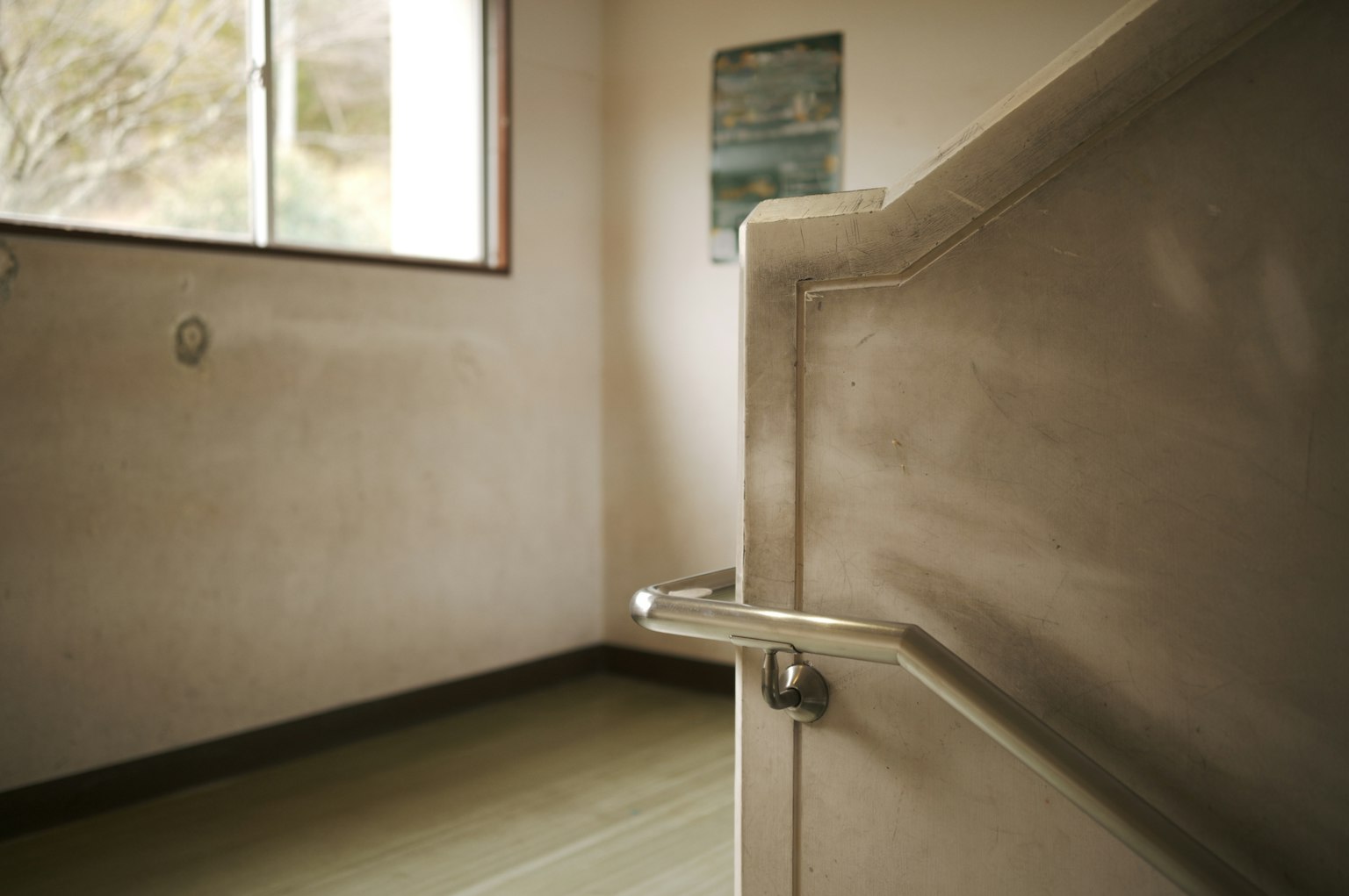 Interior de una habitación con luz natural que entra por una ventana y una barandilla visible