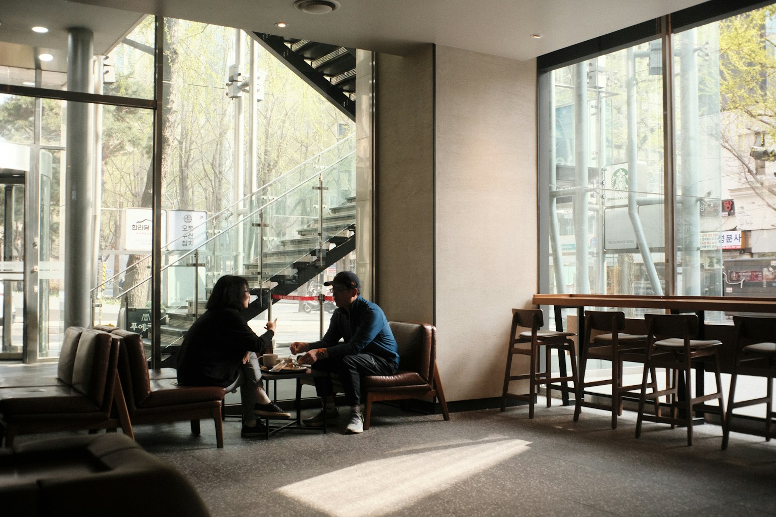 Interior kafe yang cerah dengan dua orang sedang berbicara