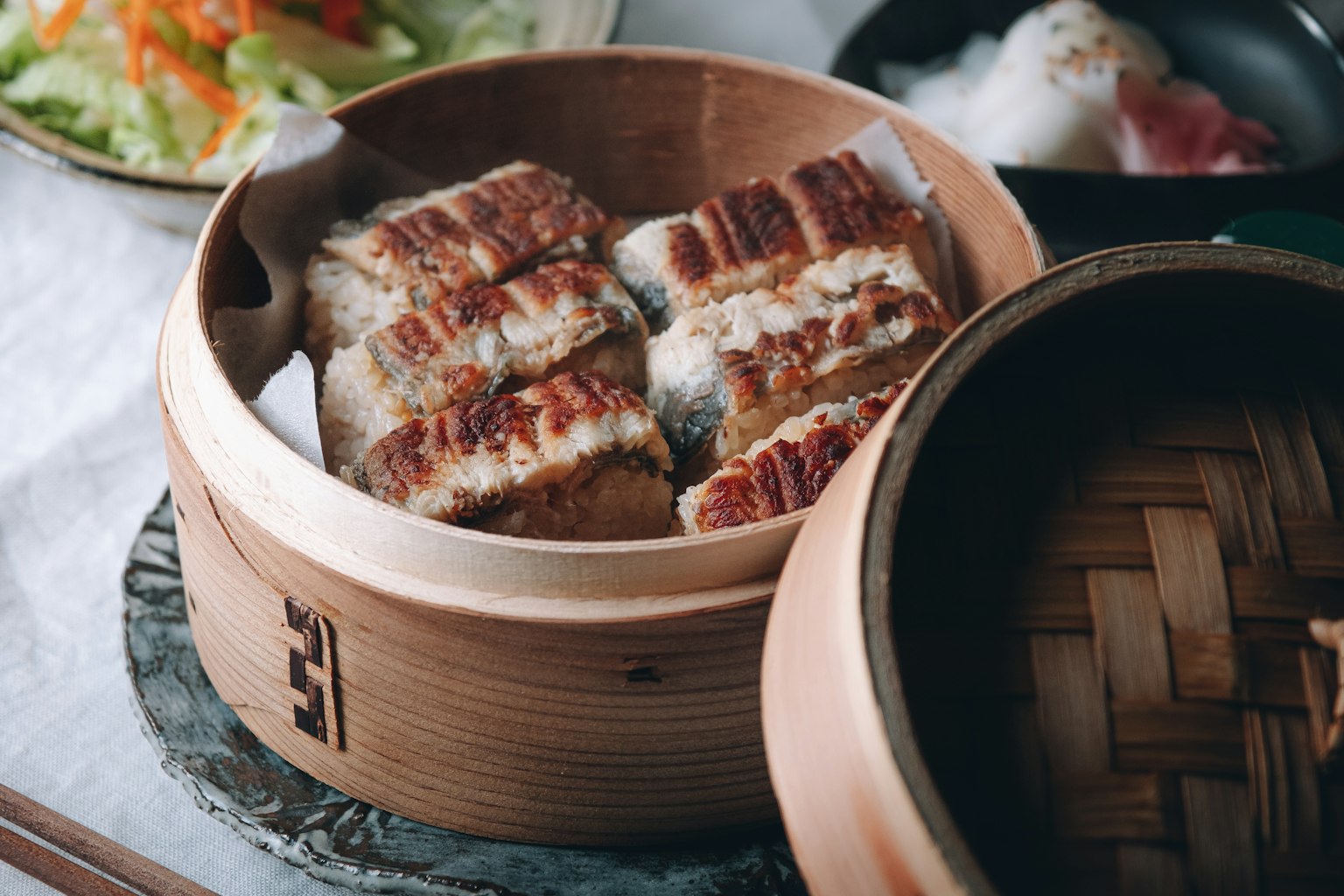 蒸笼里的烤鱼片和周围的沙拉及其他菜肴