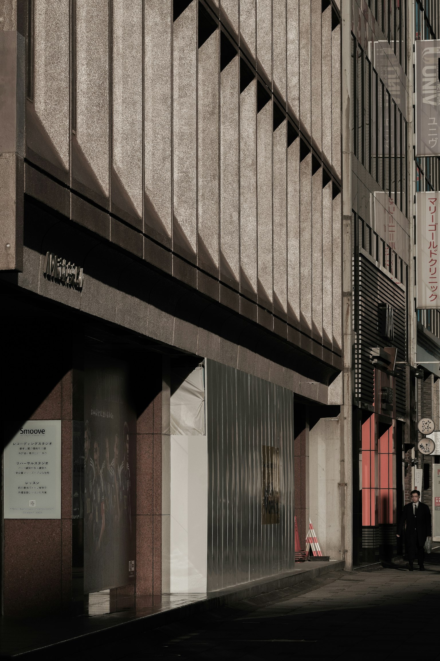 Fachada de un edificio moderno en una calle urbana oscura con sombras