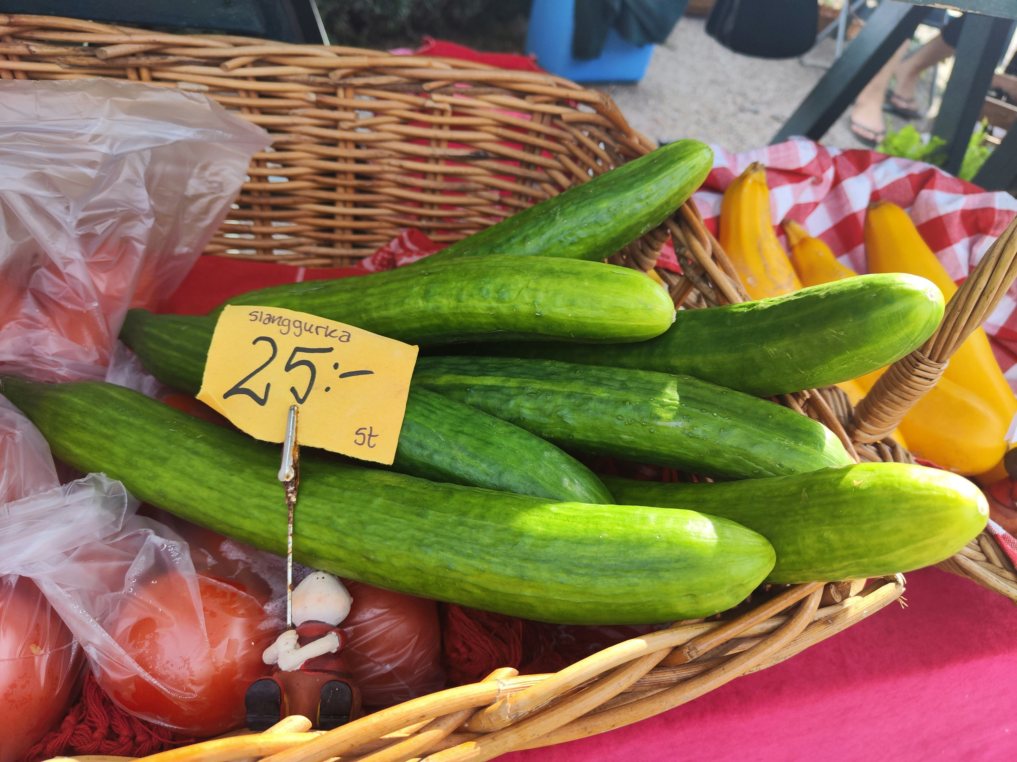 Fresh cucumbers and vegetables displayed in a basket at a market