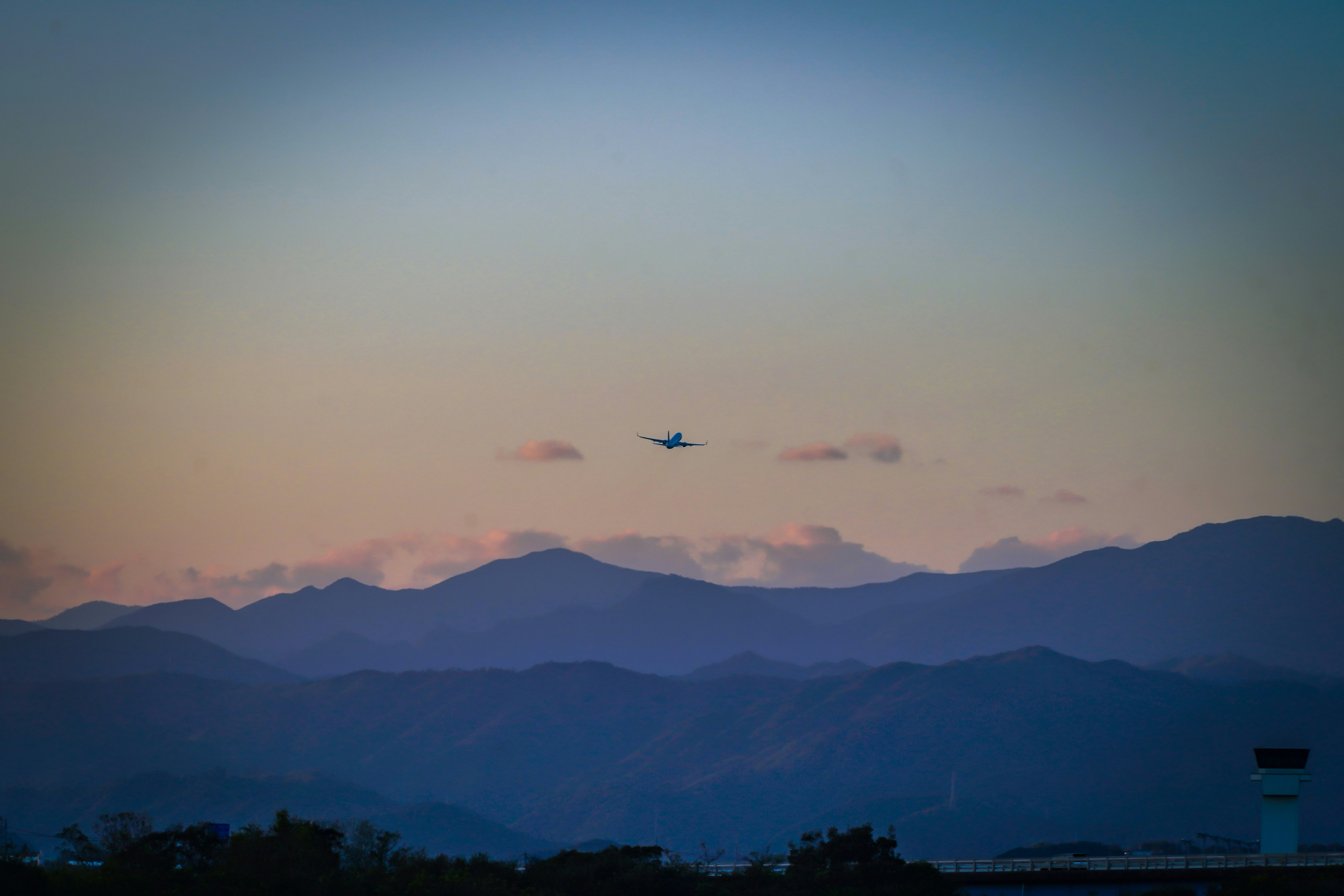 夕焼けの空と山並みを飛ぶ飛行機雲のある風景