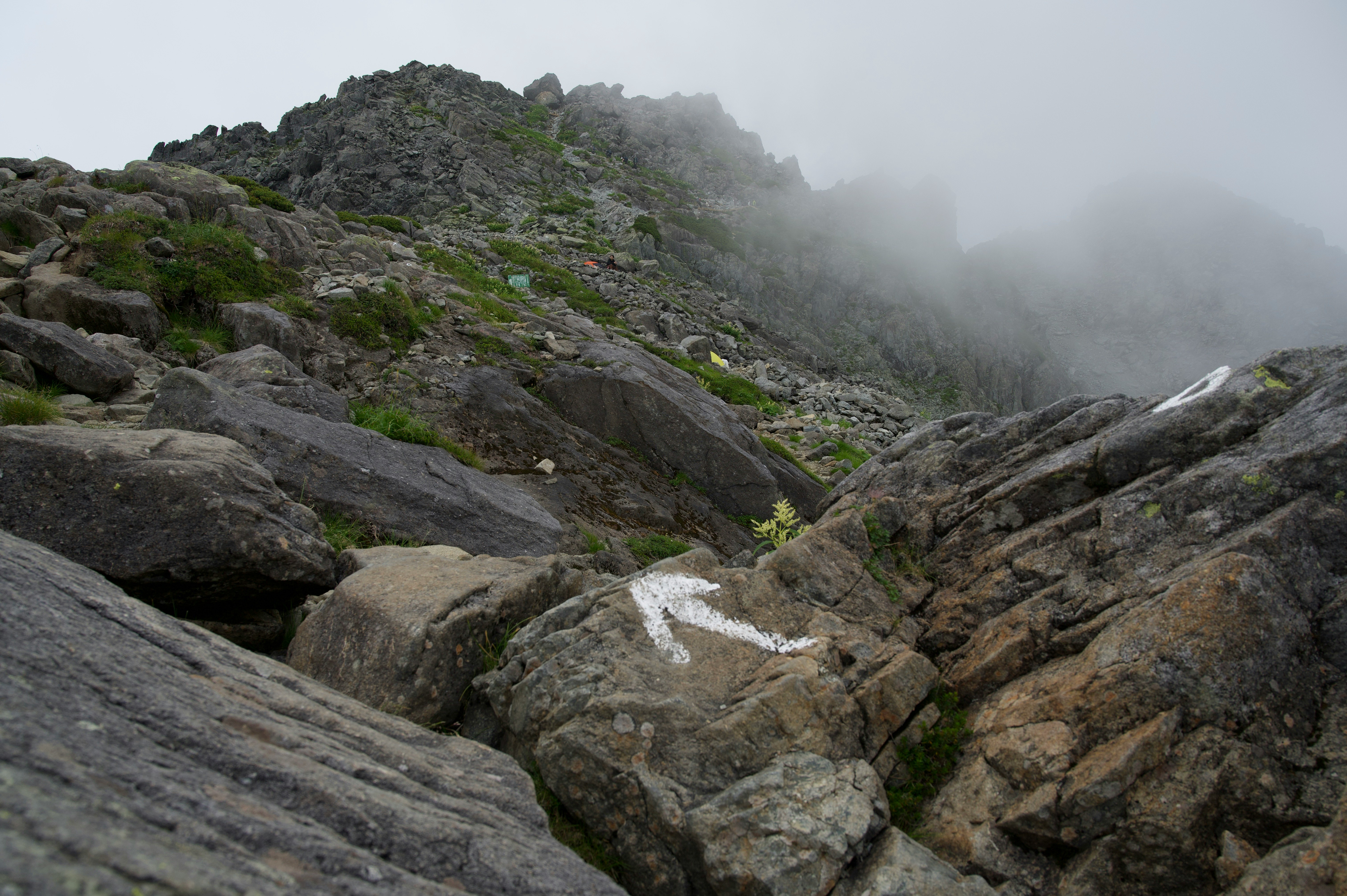 cresta montuosa rocciosa nella nebbia con sentiero