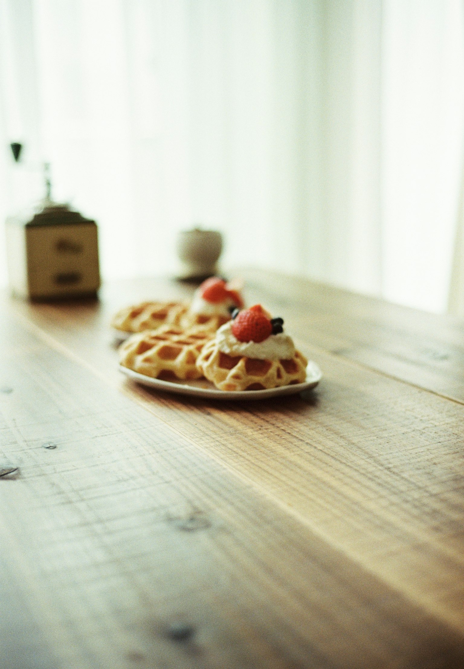 Waffles cubiertos con crema y fresas sobre una mesa de madera