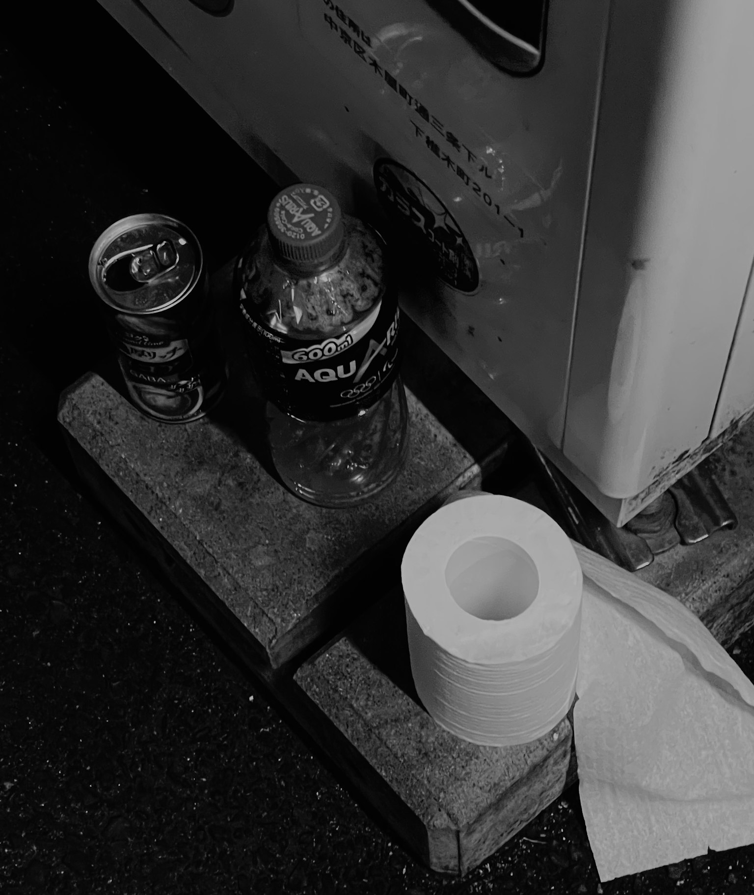 Immagine in bianco e nero con una lattina di birra, una bottiglia di plastica e carta igienica