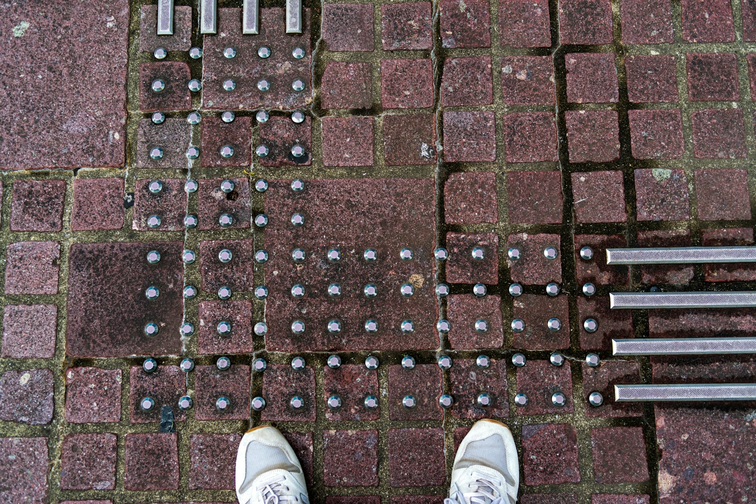 Motif de barres métalliques et de plaques circulaires au sol avec des baskets