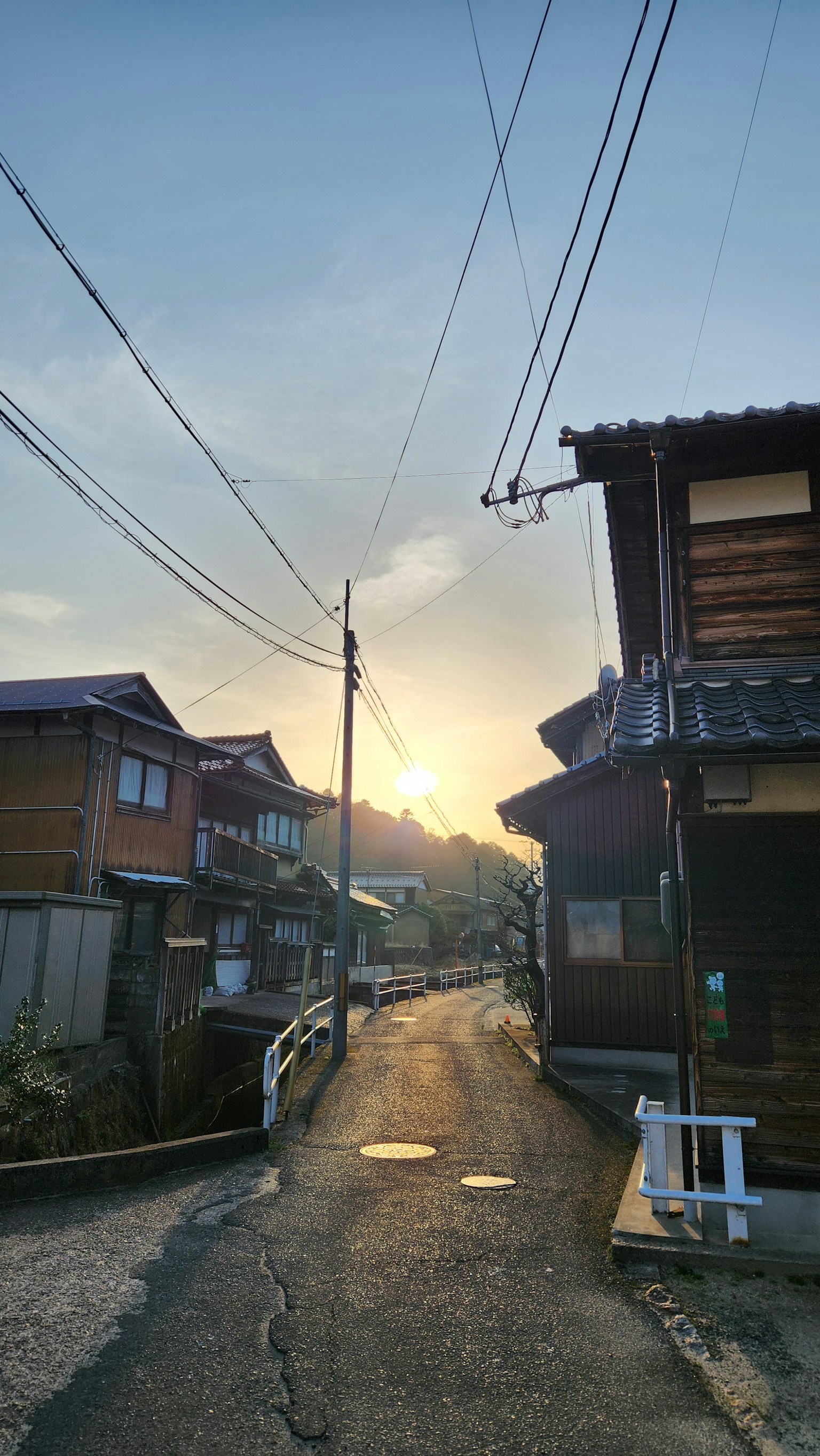 Strada residenziale tranquilla al tramonto con case in legno allineate e il tramonto visibile nel cielo