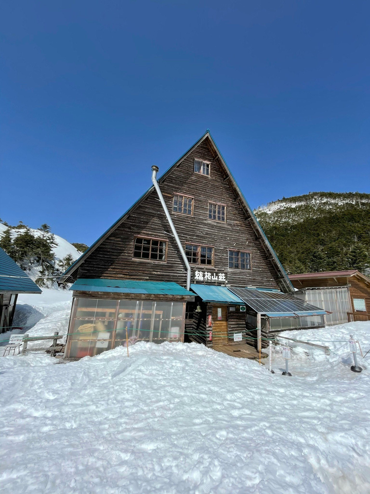 tòa nhà gỗ kiểu cabin trên núi phủ tuyết kèm nhà kính