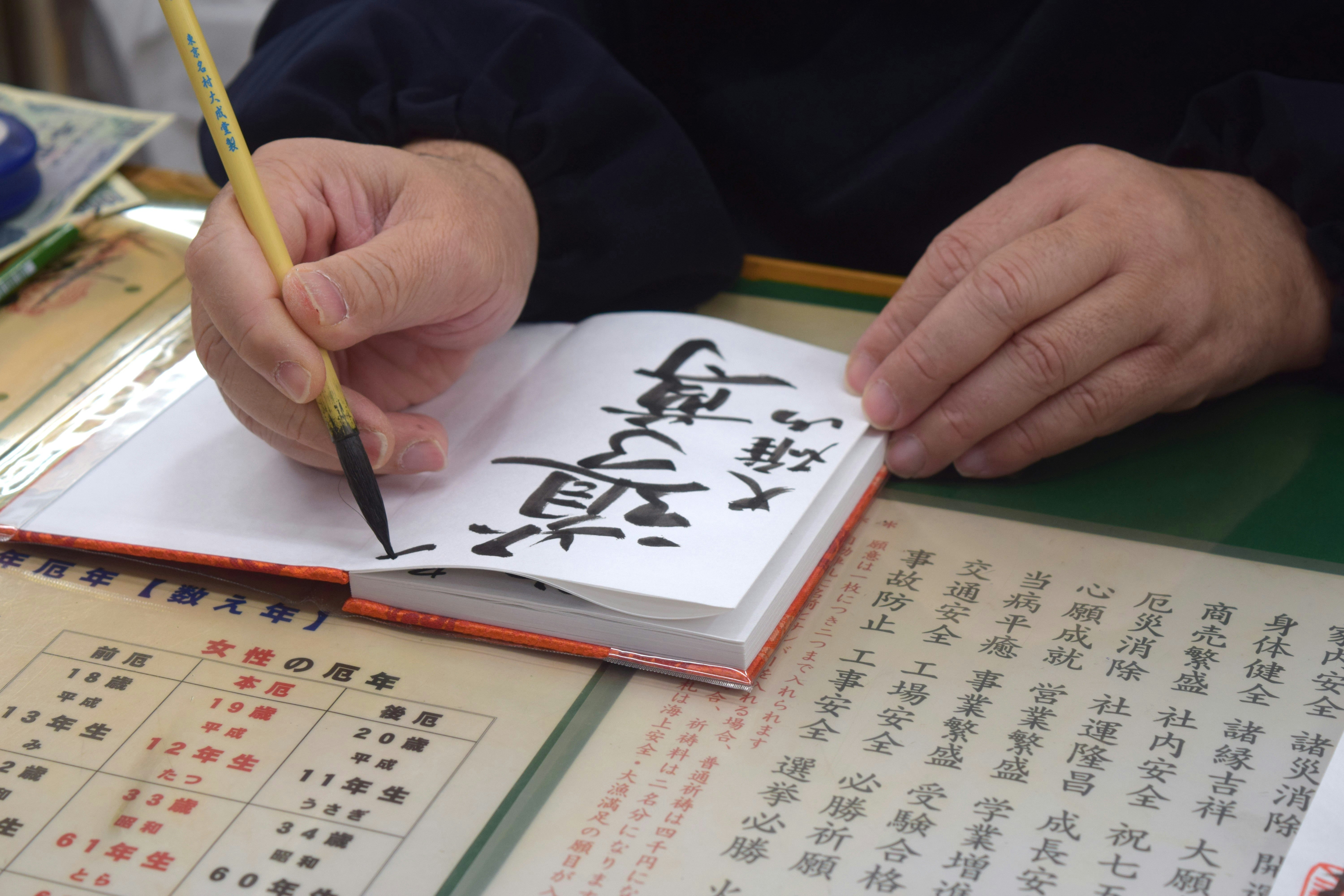 筆で御朱印帳に毛筆の文字を書く手元