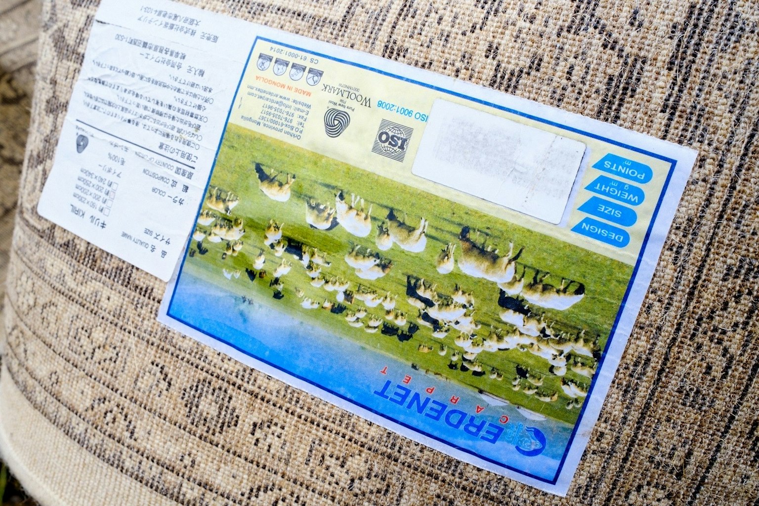 Image of a textile product label featuring a landscape with various animals and a blue water element