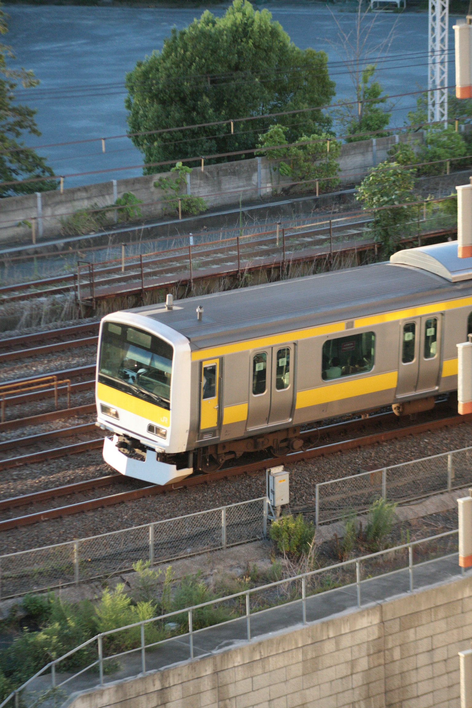 Sebuah kereta kuning dan perak melaju di rel