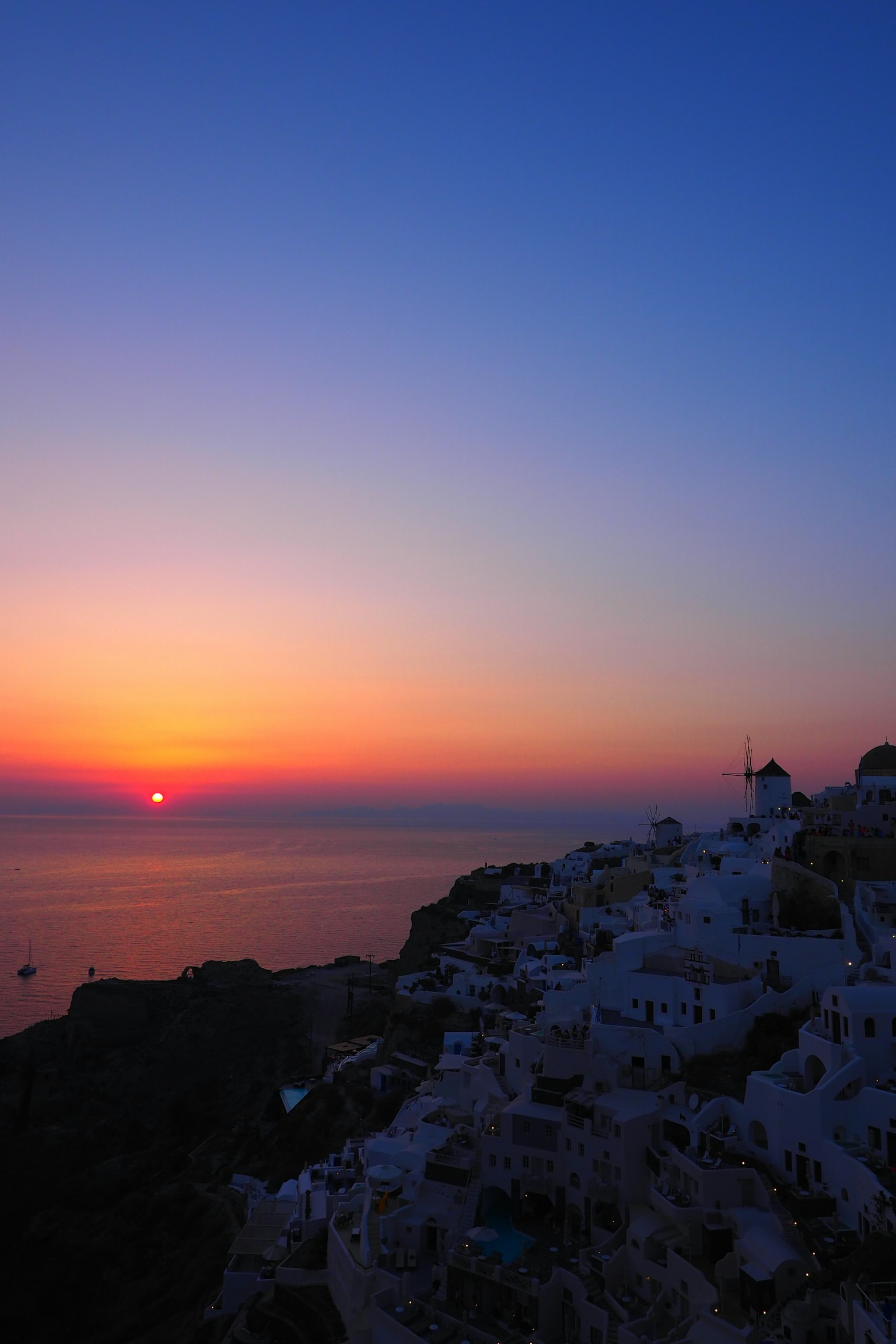 Beeindruckender Sonnenuntergang über dem Ägäischen Meer mit weißen Gebäuden von Santorin