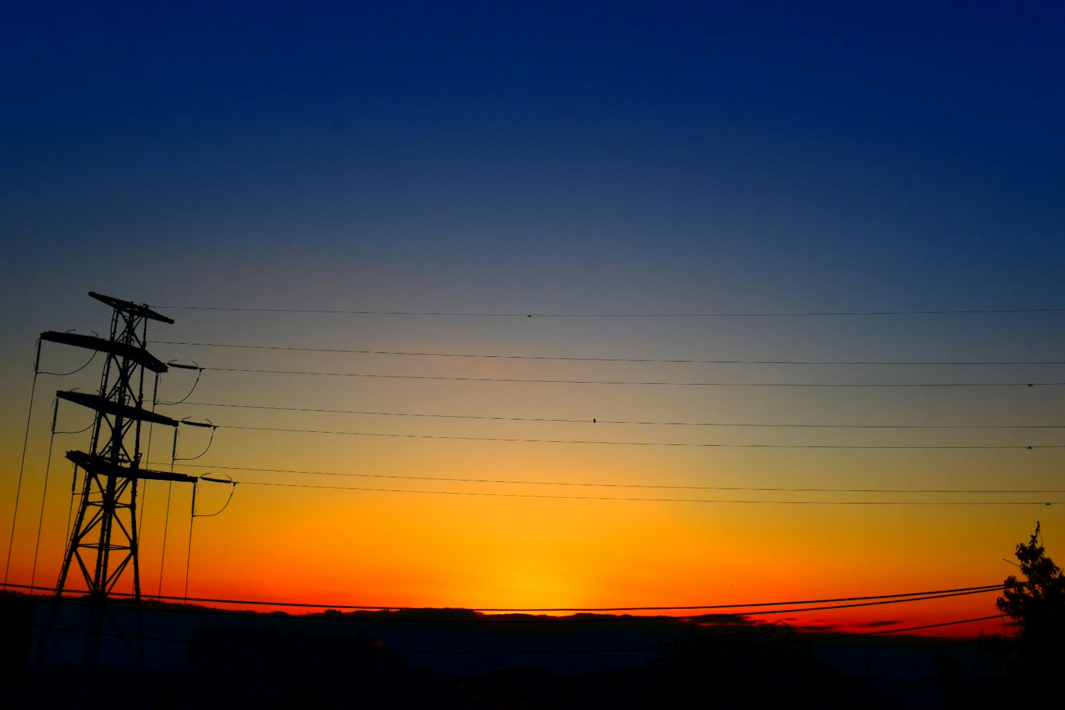 Beeindruckender Sonnenuntergang mit Silhouette von Stromleitungen vor lebendigen Farben