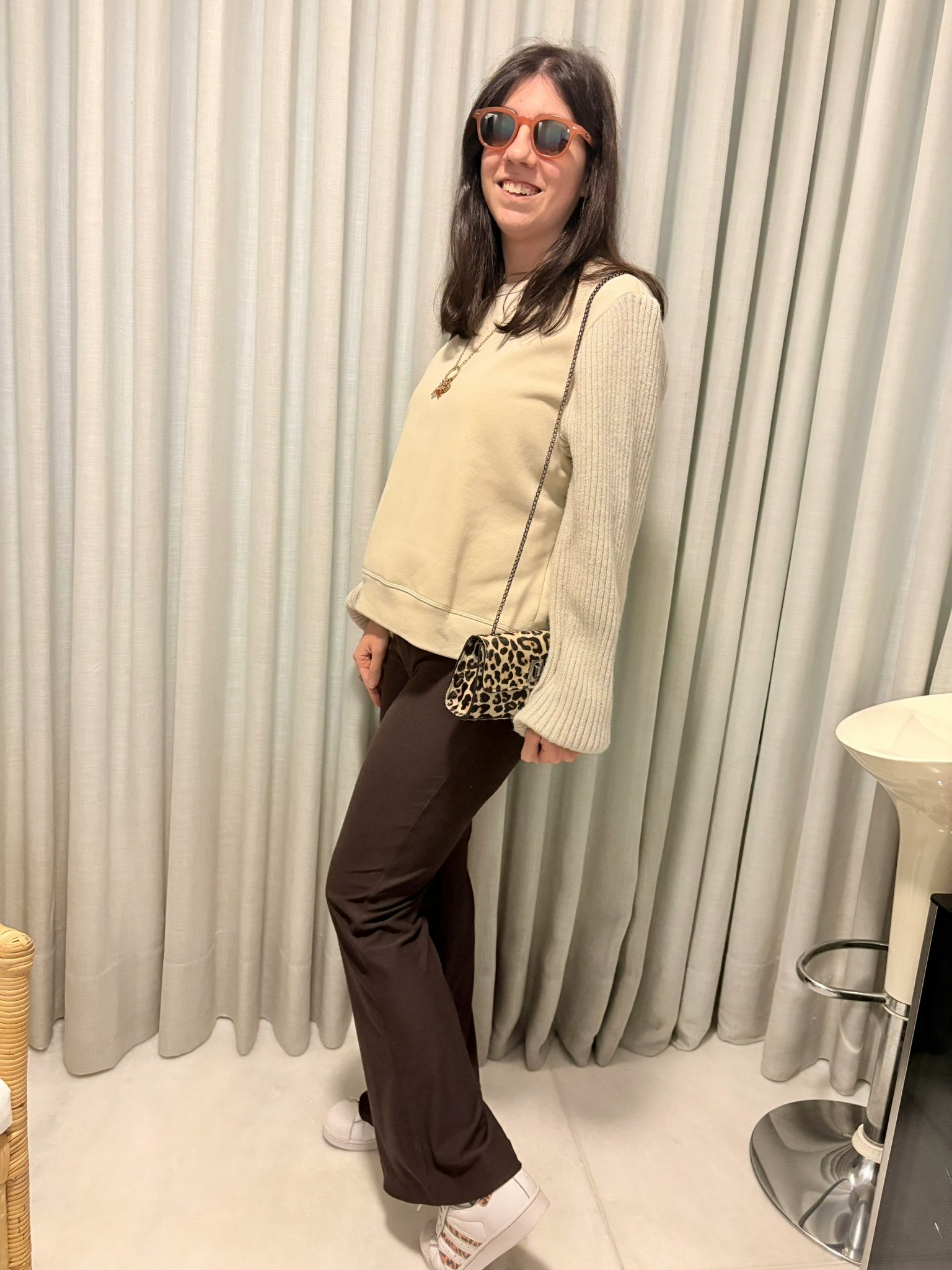 ベージュのニットとサングラスの女性がポーズをとる屋内スタジオ風