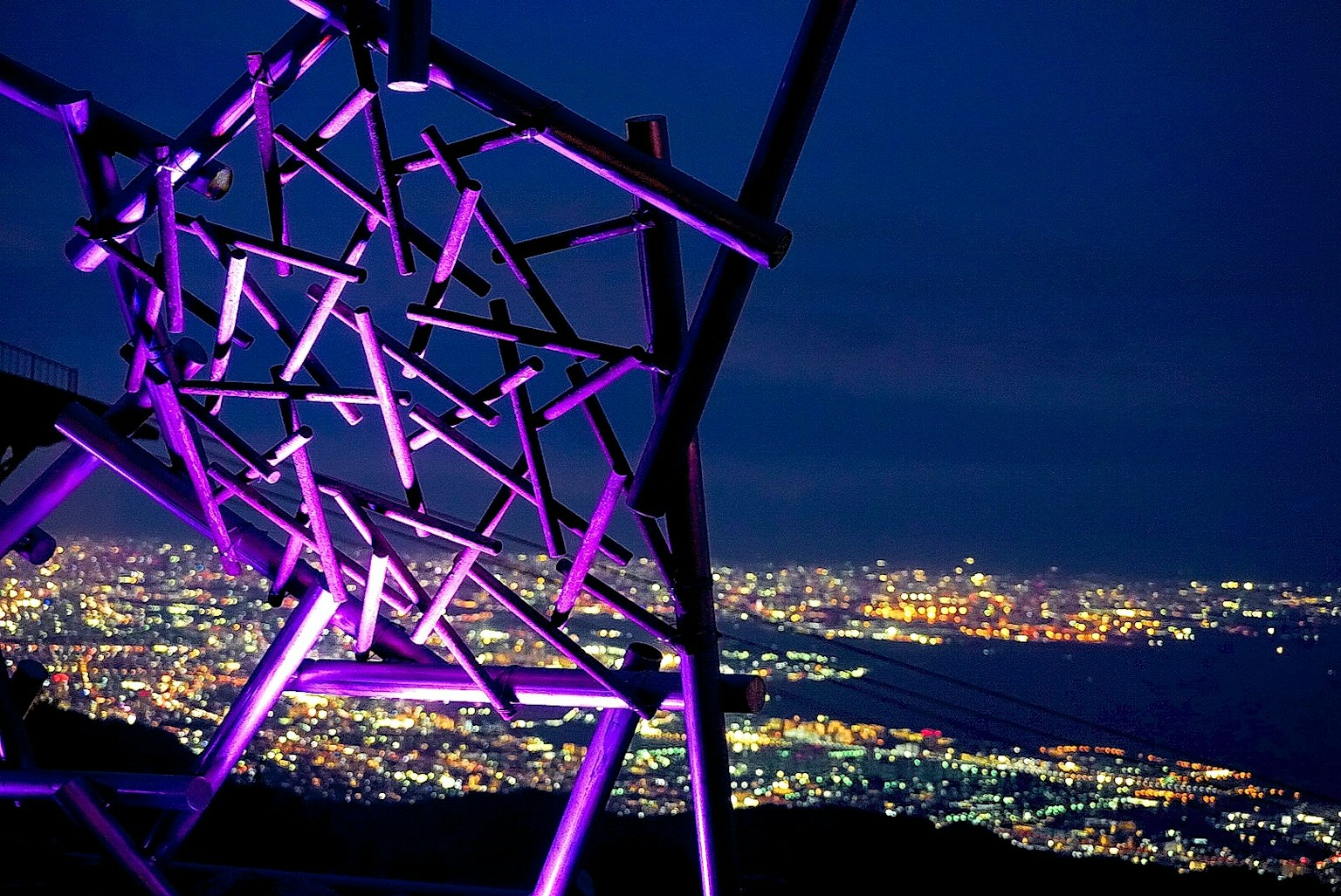 夜景下的紫色照明抽象雕塑與城市天際線