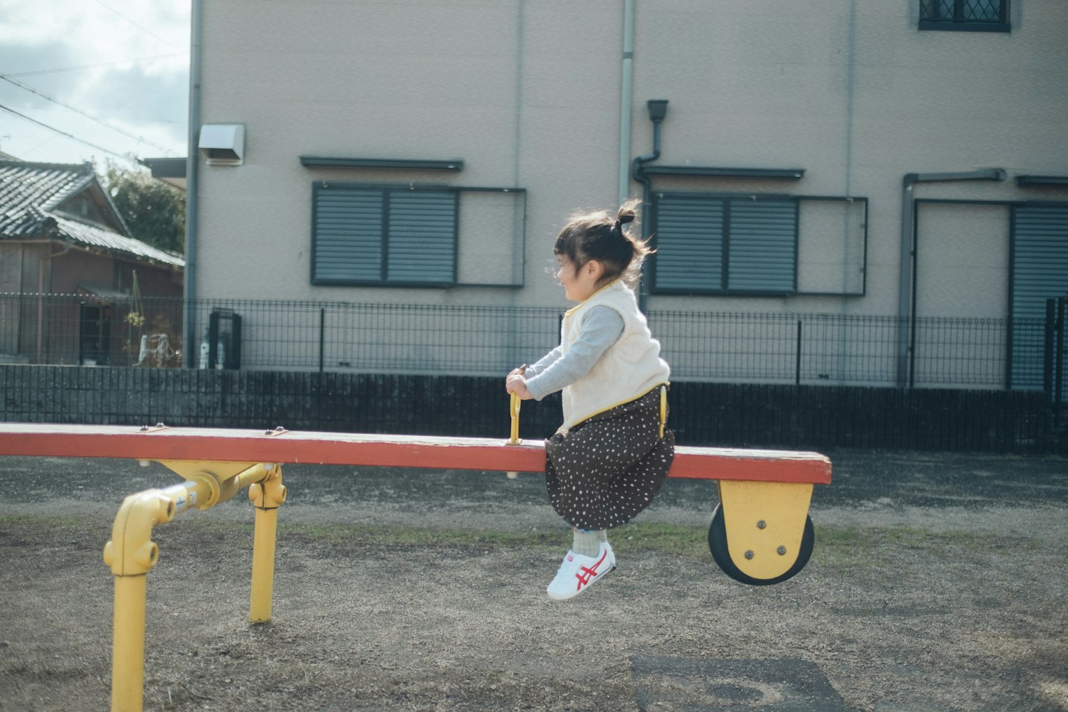 Kind sitzt auf einer Wippe in einem Spielplatz